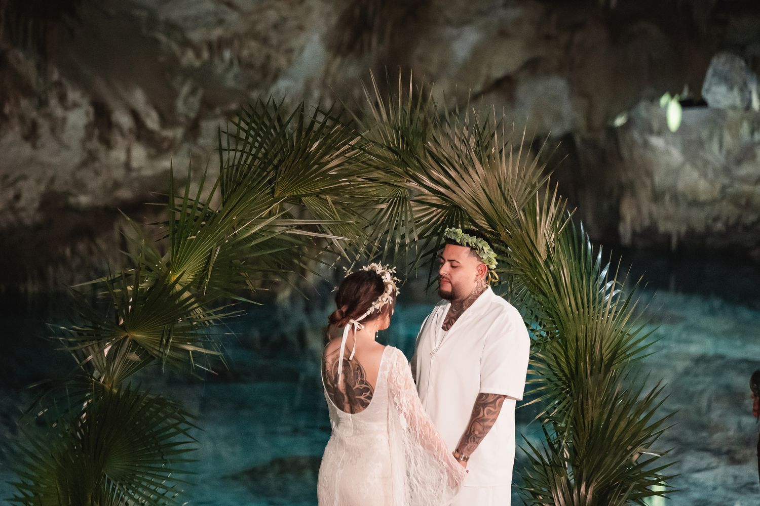 Romantic moment captured by turquoise cenote waters surrounded by tropical plants.