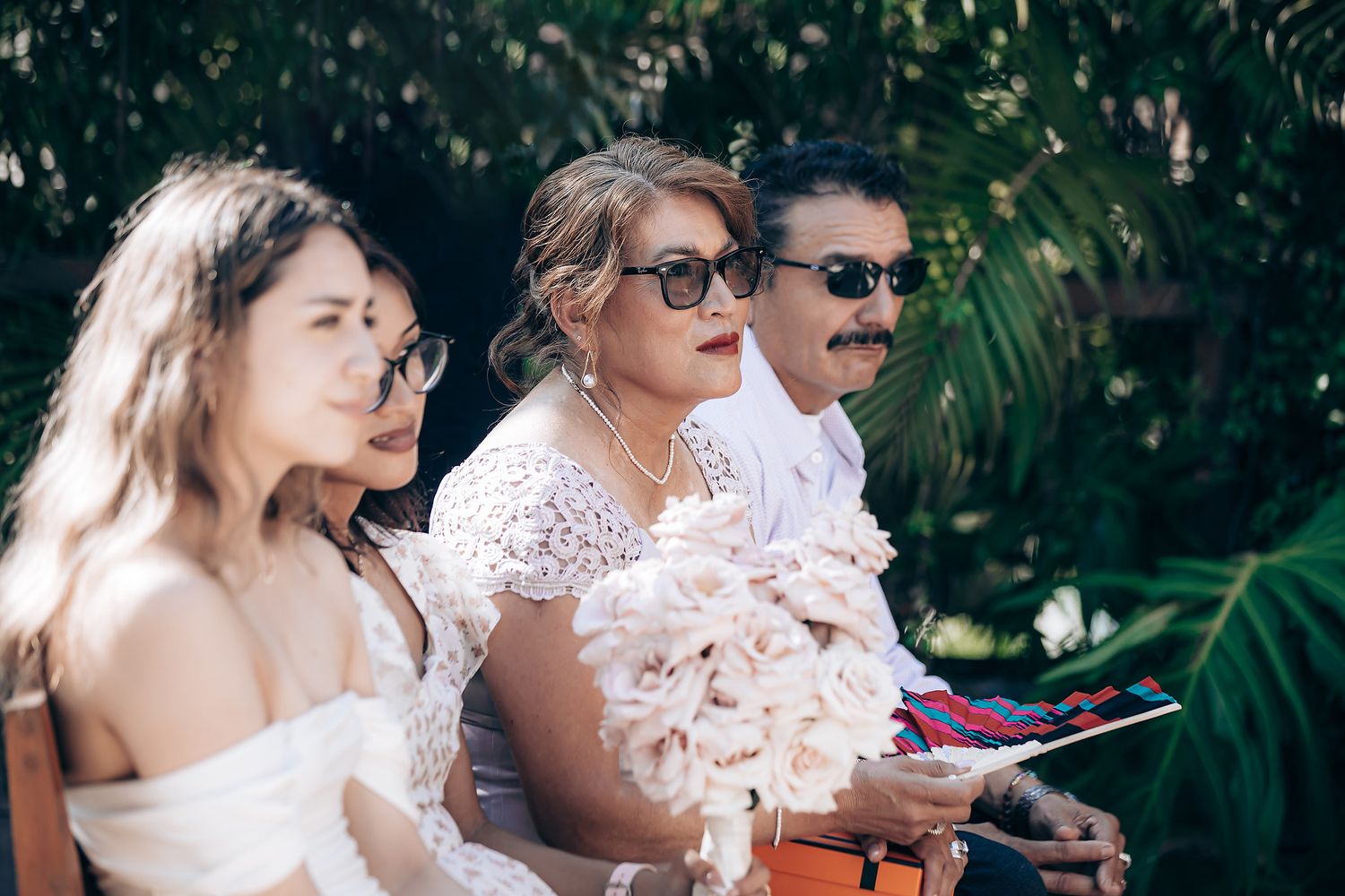 Wedding party members enjoy drinks and conversation during an outdoor garden reception celebration.