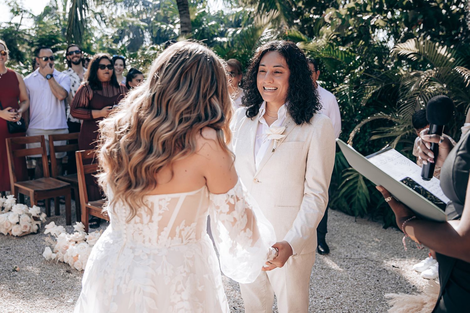 A couple shares their first dance at an outdoor wedding reception surrounded by guests and natural scenery.