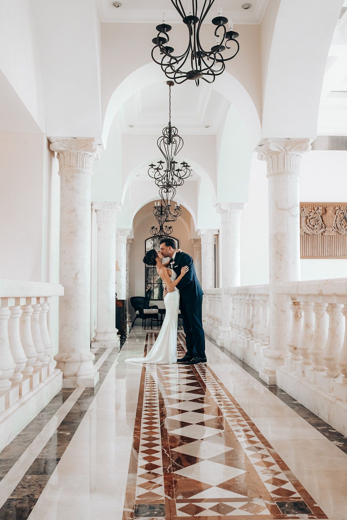 Romantic wedding portraits in a bright marble corridor with ornate architectural details.