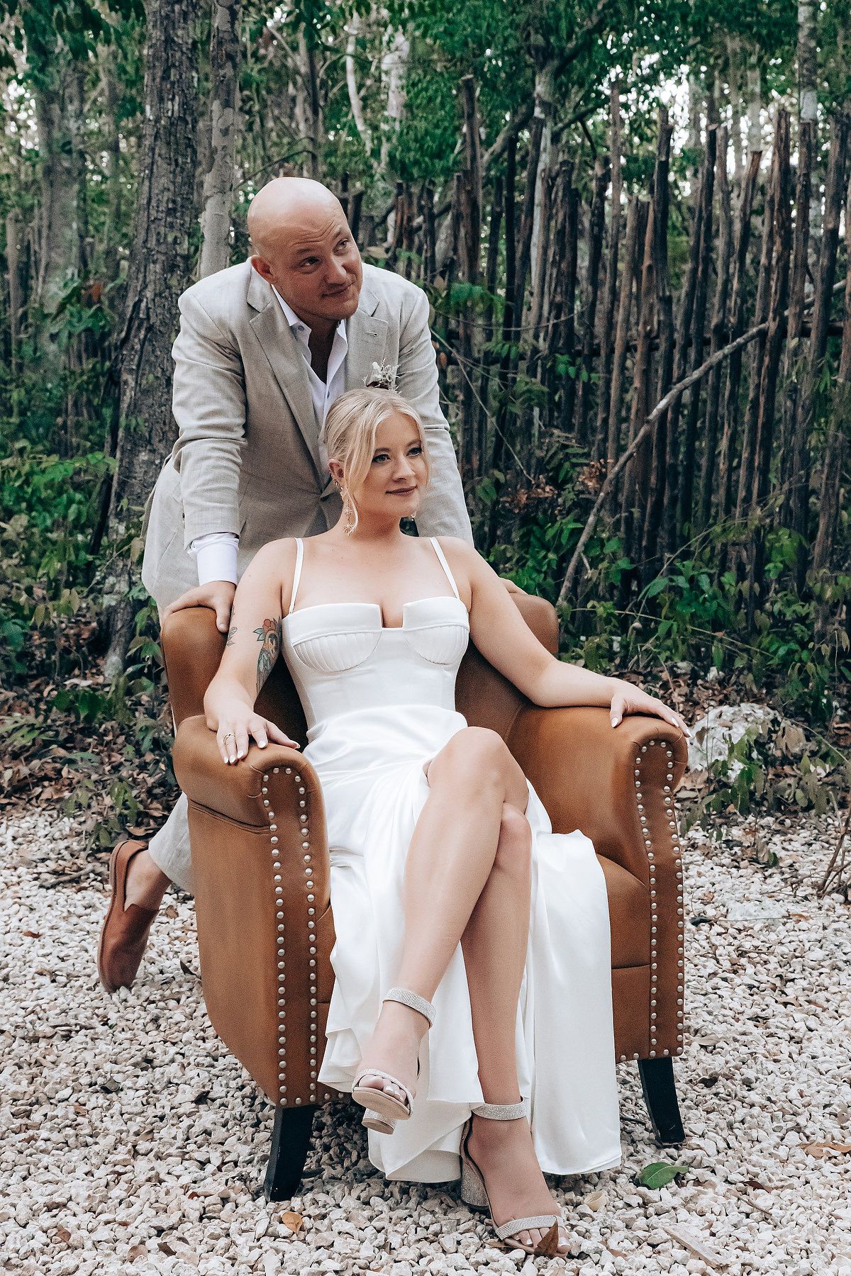 Wedding celebration moment on brown leather chairs in a natural outdoor setting.