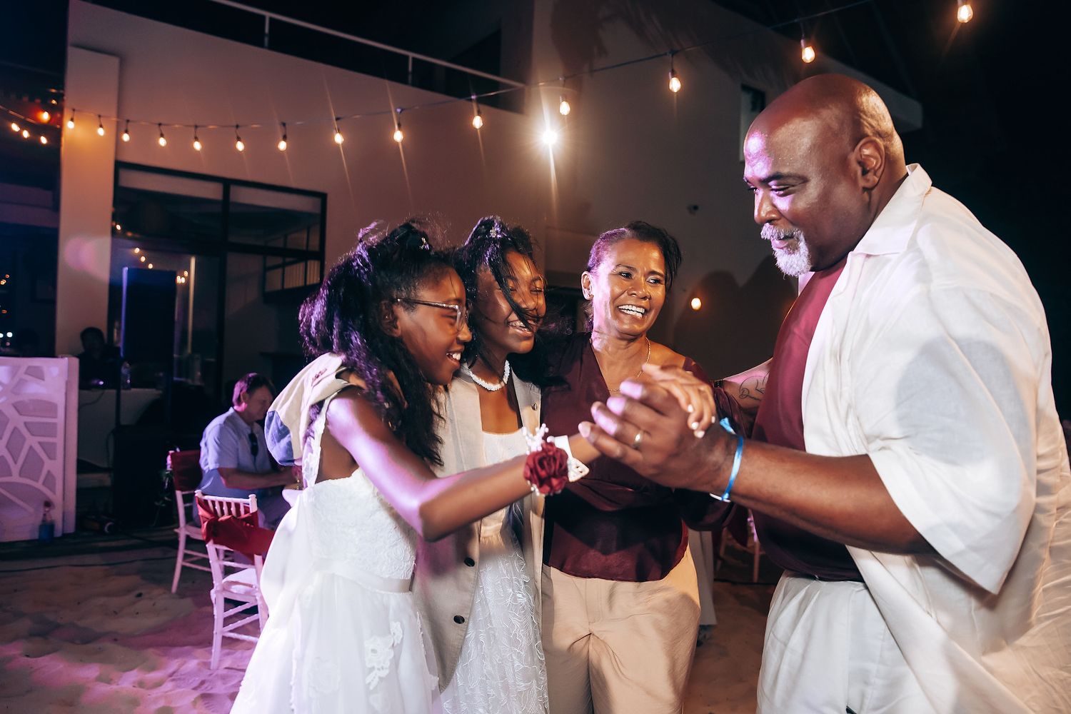 Wedding reception guests dancing together under warm lighting at an evening celebration.