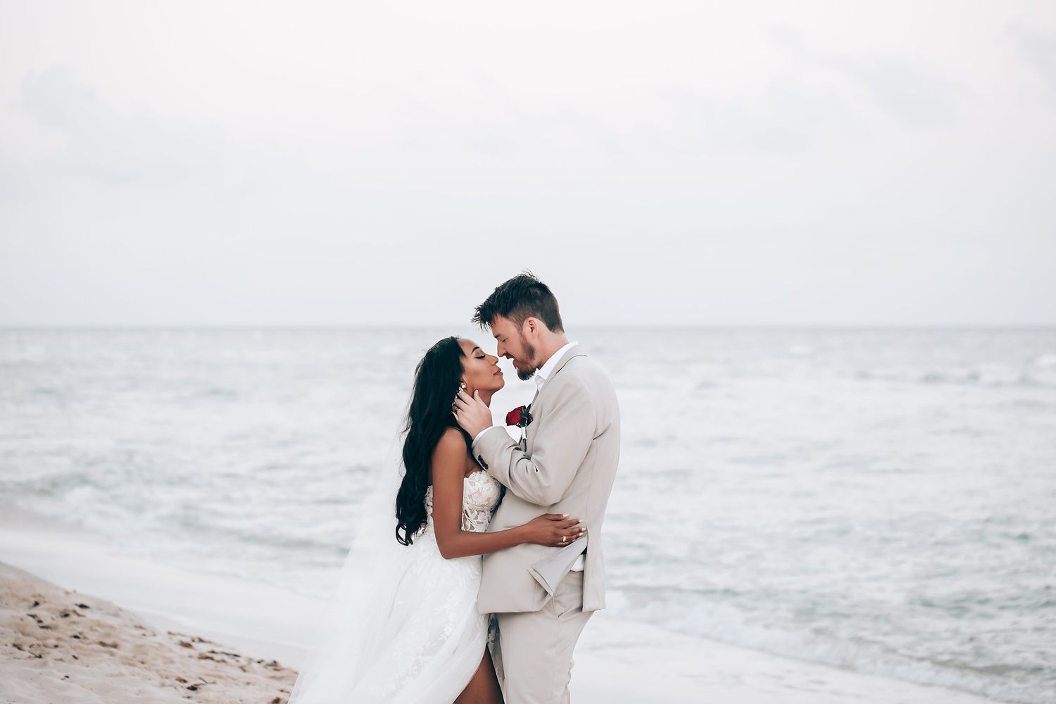 Romantic beach wedding photoshoot with ocean waves in the background.