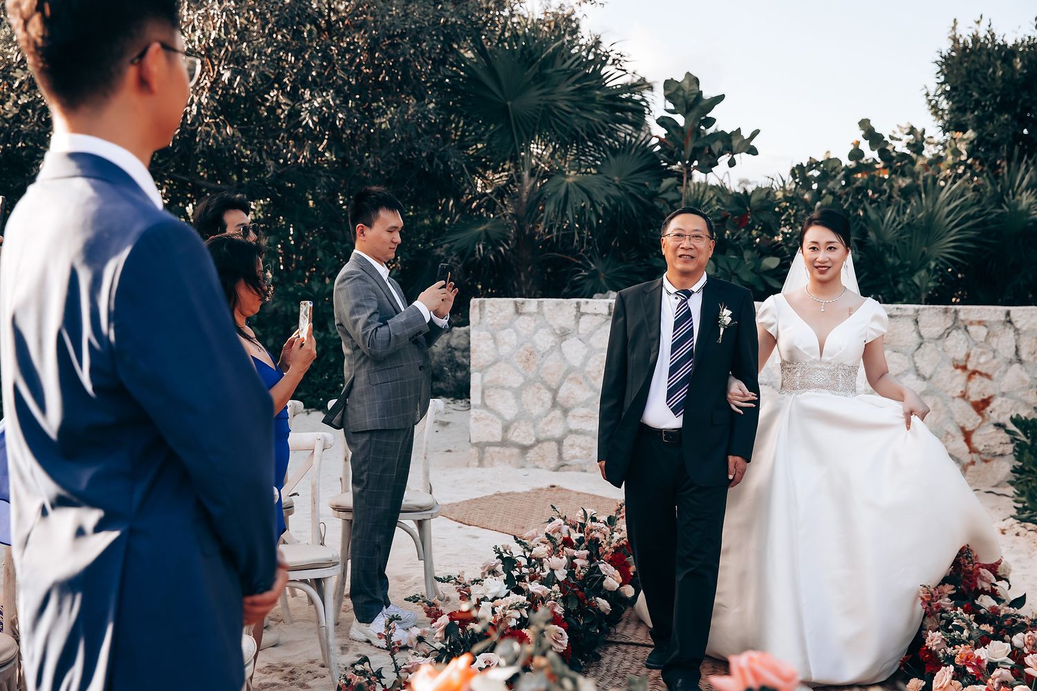 Wedding ceremony taking place under a rustic stone arch with floral decorations.