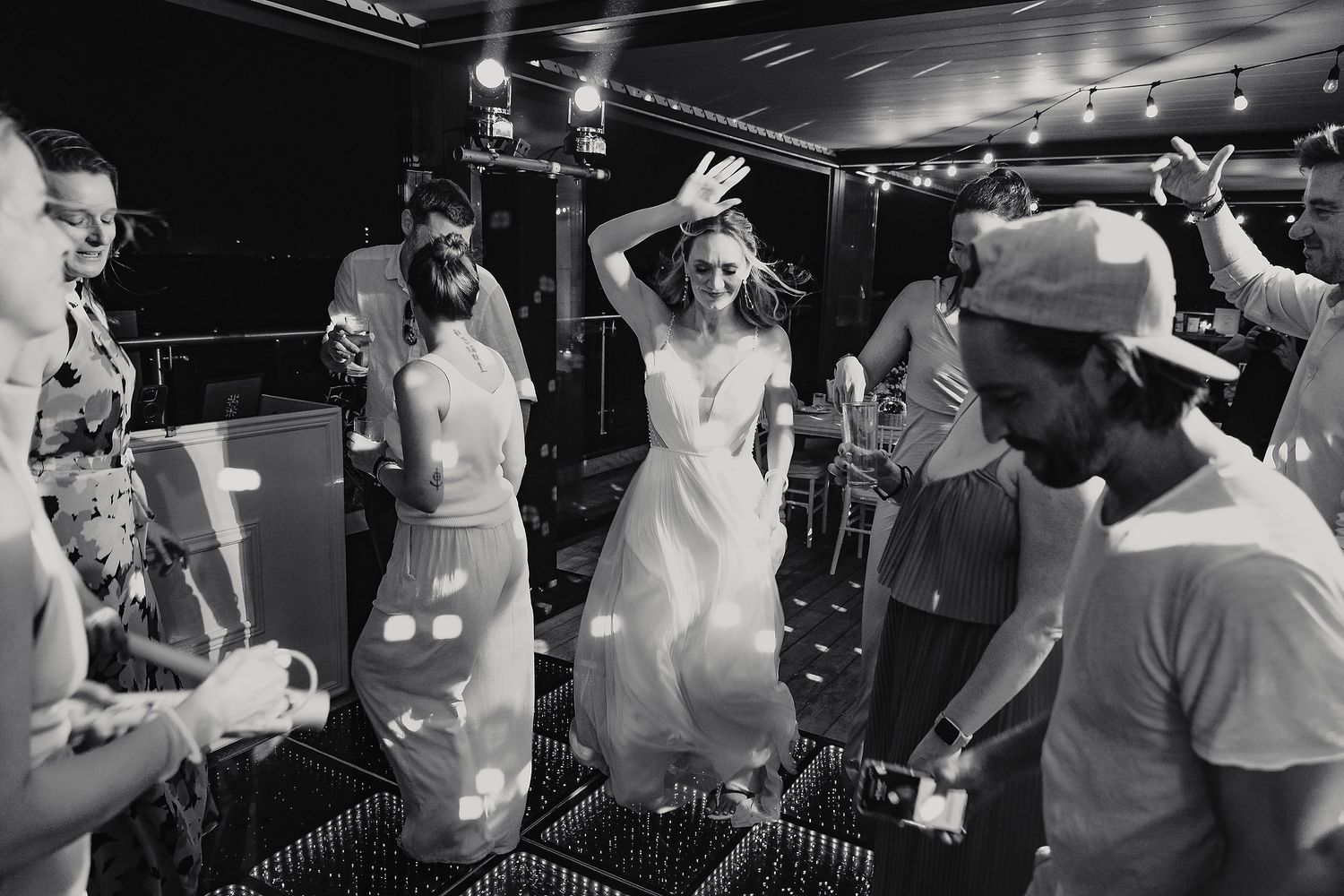 Black and white shot of party guests dancing and celebrating at a lively reception.