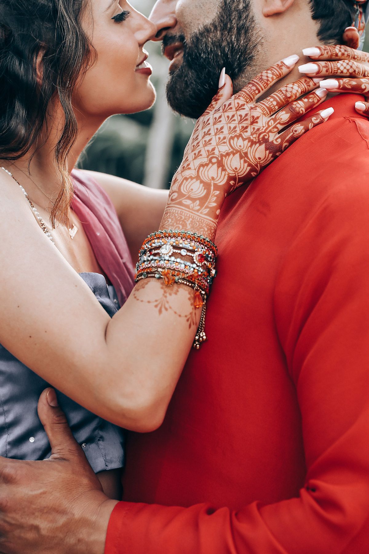 Close-up shots showing traditional henna-adorned hands and bangles against a red outfit in an intimate moment.