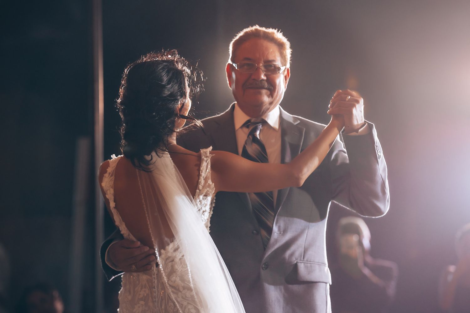 Wedding guests dance and celebrate under dramatic lighting at an evening reception.