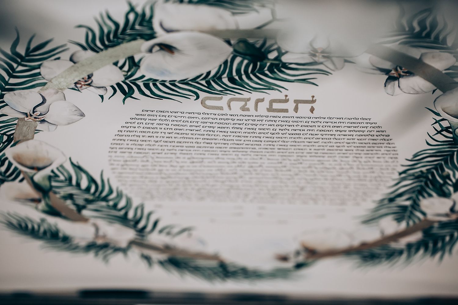 A decorative wedding ketubah document with delicate fern leaf designs around the border.