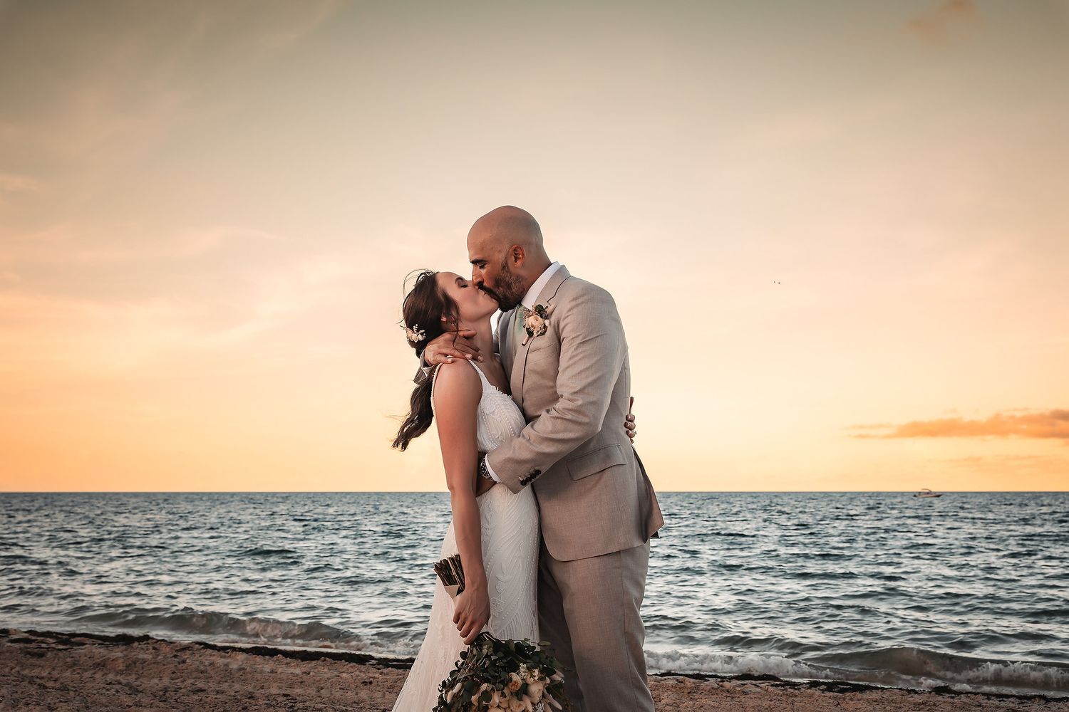 A romantic sunset beach wedding photo with the ocean horizon in the background.
