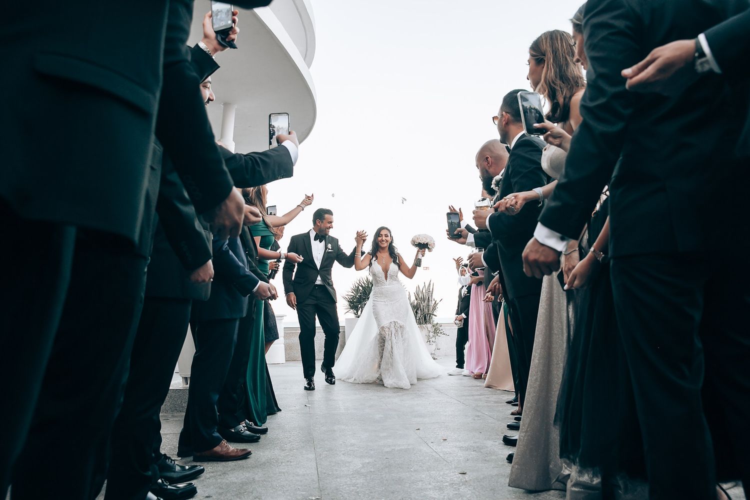 Wedding ceremony guests seated in rows at an oceanfront venue.