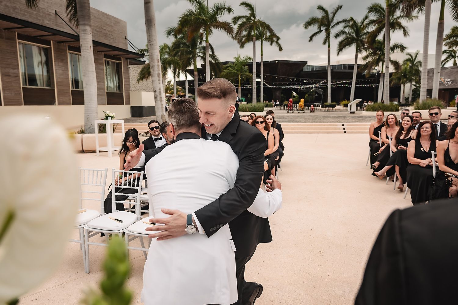 Outdoor wedding ceremony setup with palm trees and white chairs arranged on a sunny tropical day.