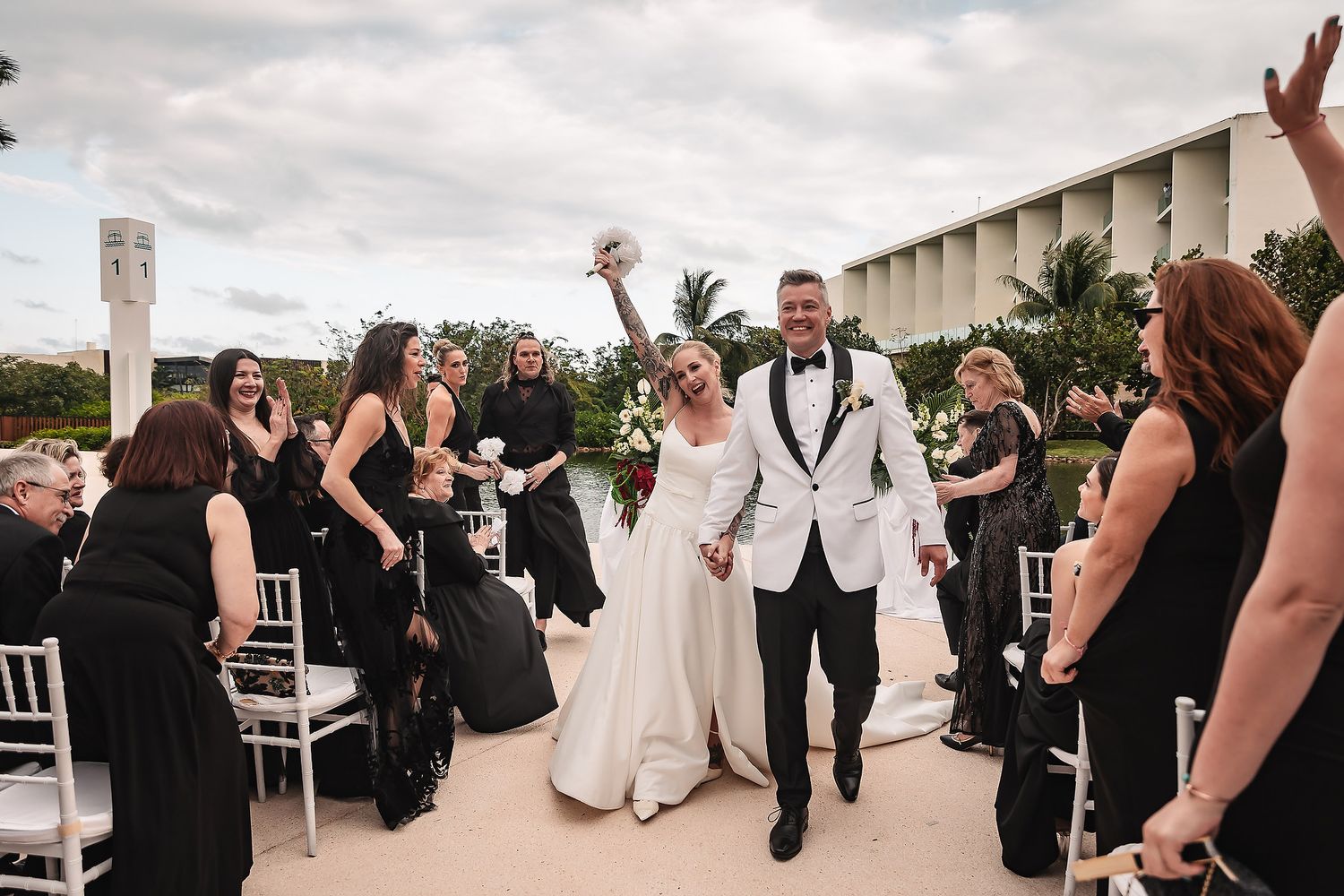 Wedding guests celebrating at an outdoor reception venue with cloudy skies.