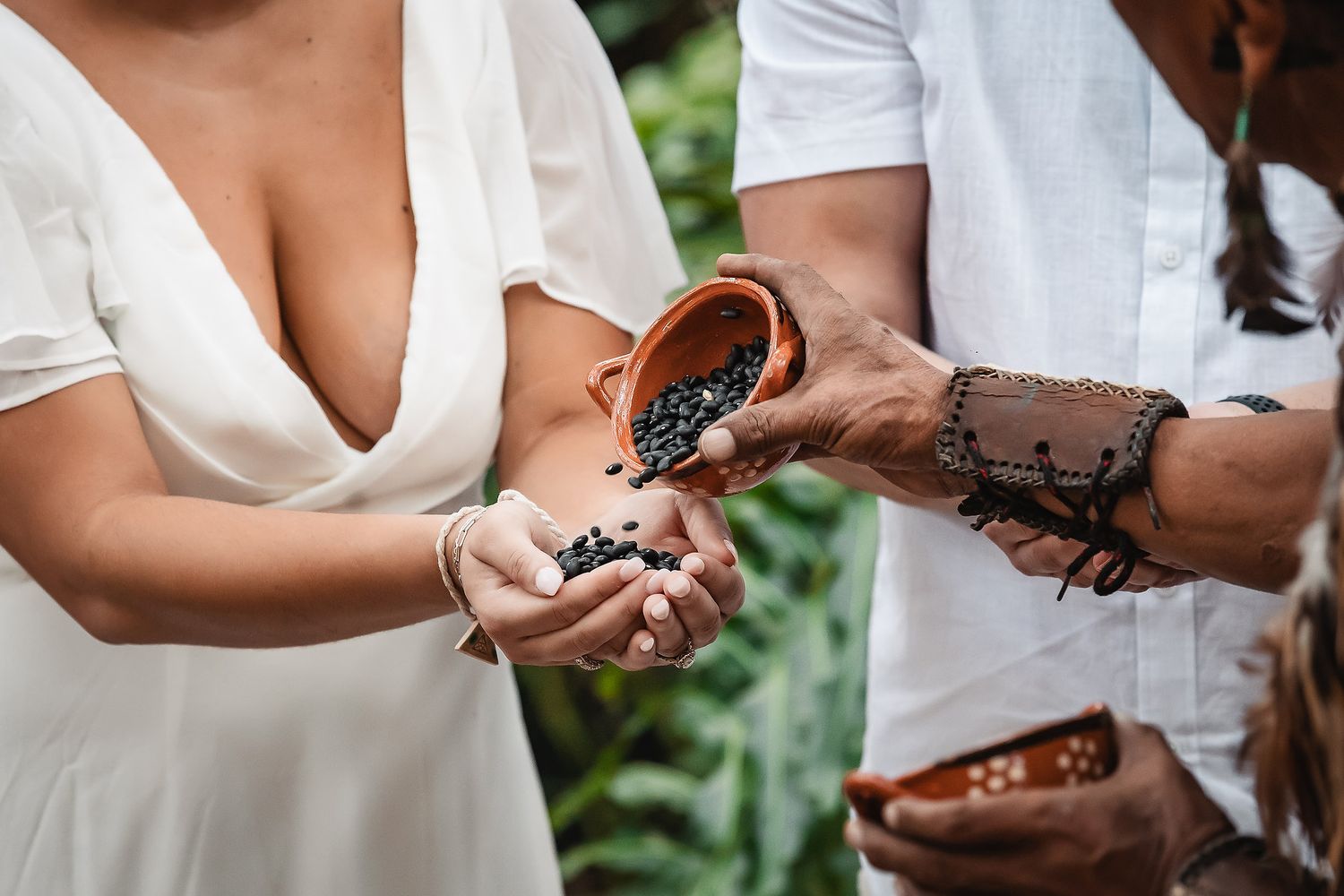 Close-up of hands during traditional Mayan wedding ceremony exchanging ritual items.