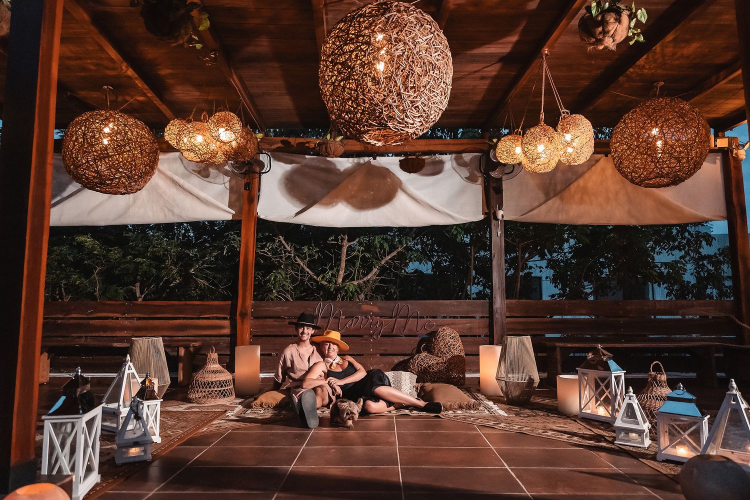Rustic wooden pavilion decorated with woven sphere lanterns and ambient lighting.
