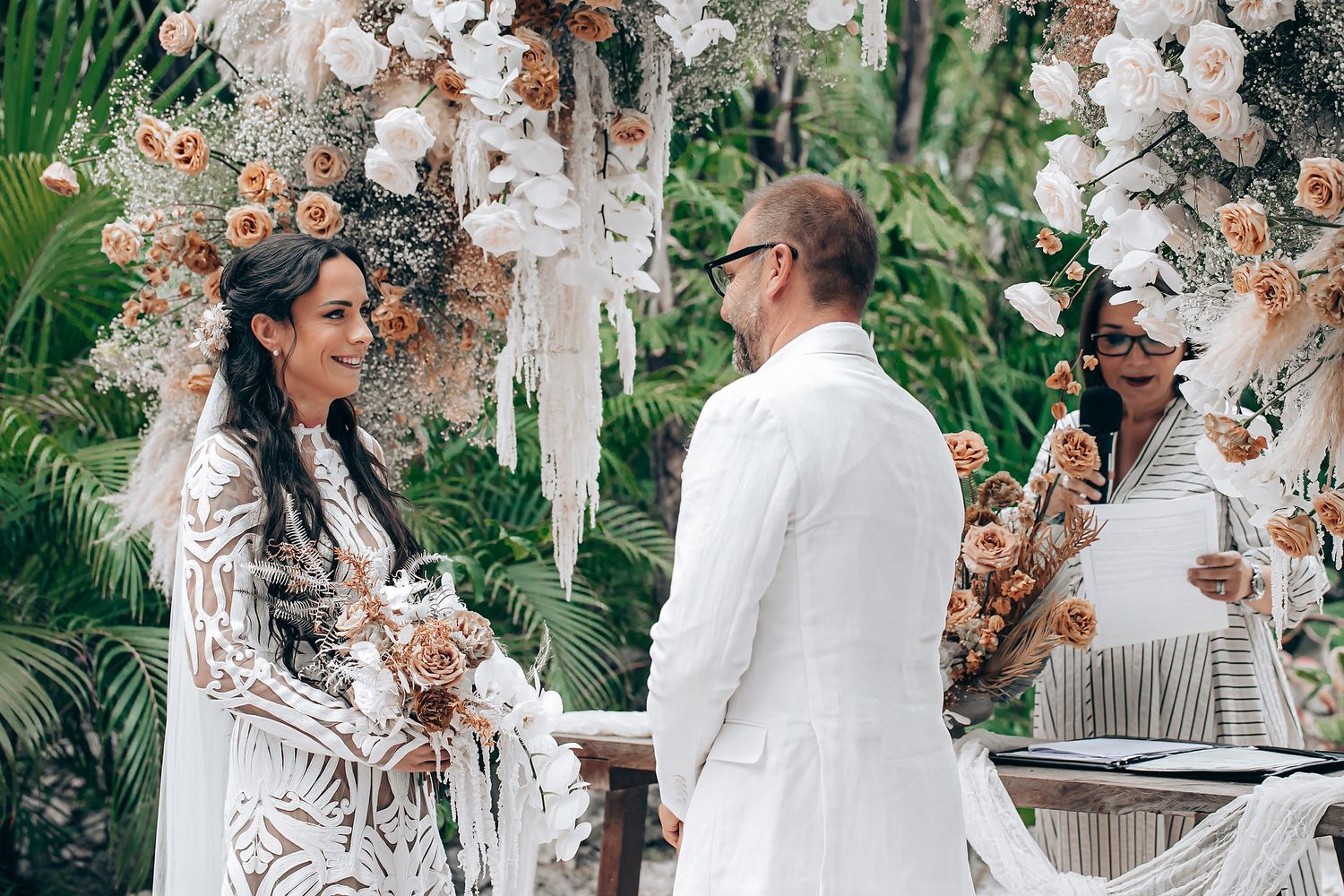 Romantic wedding ceremony in a lush garden setting with white floral arrangements and elegant decor.