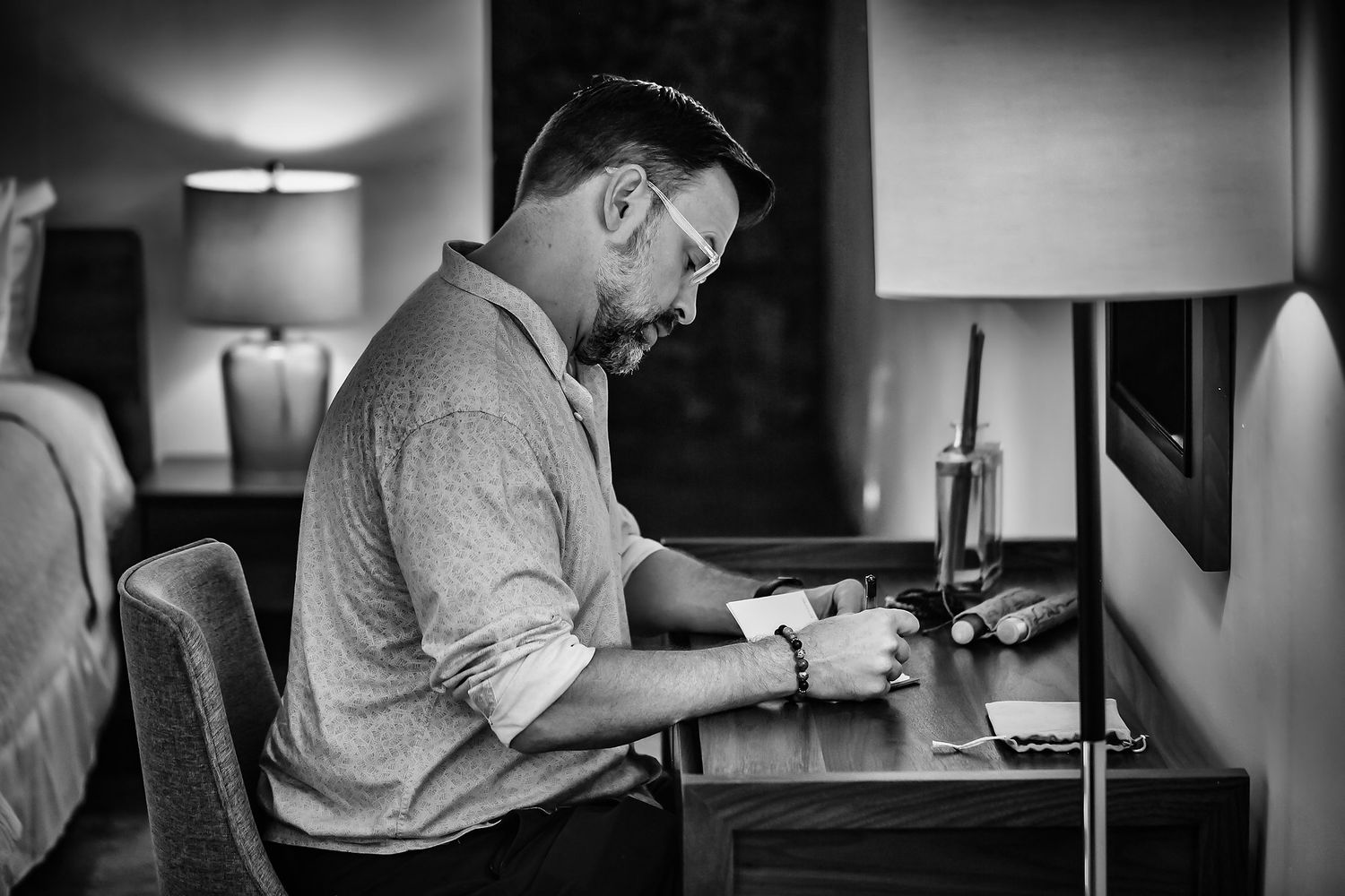 Black and white photo series showing someone writing at a desk with a lamp in various compositions.
