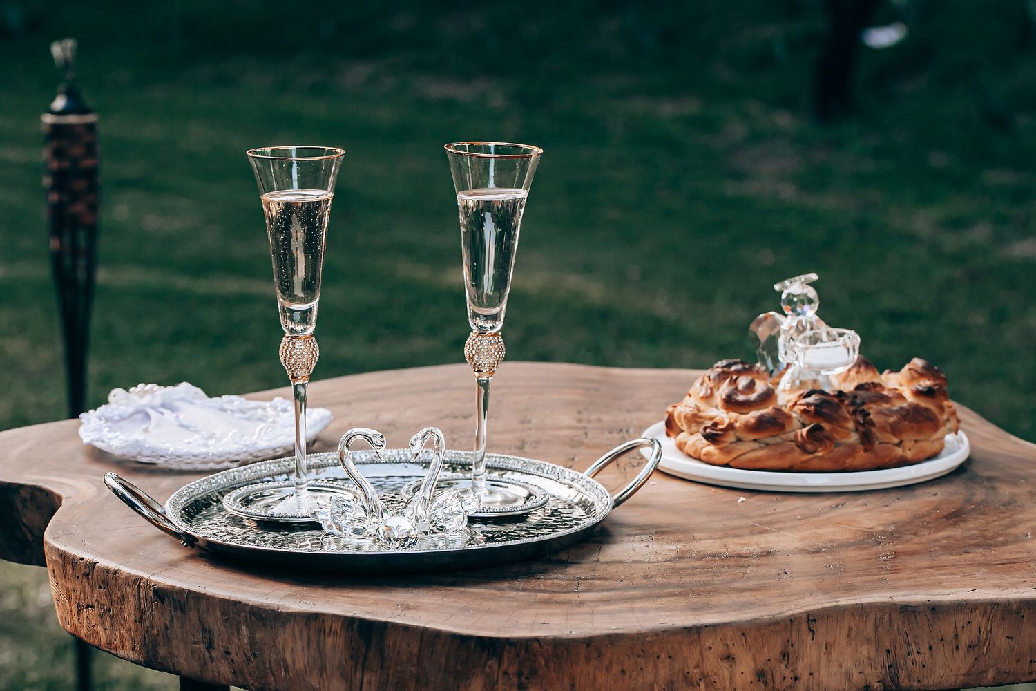 Two champagne flutes and a dessert plate sit on a rustic wooden surface with a green background.
