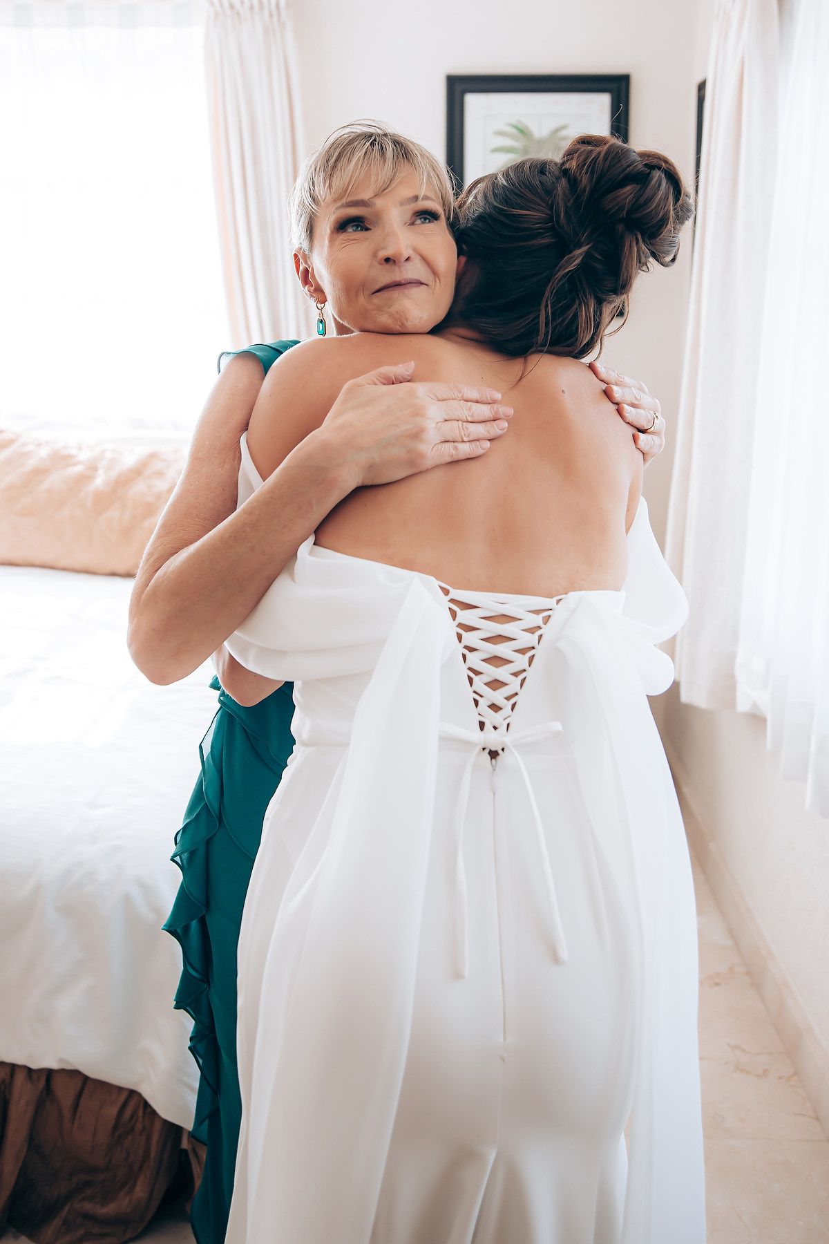 A series of photos showing someone helping to lace up the back of an elegant white wedding dress.
