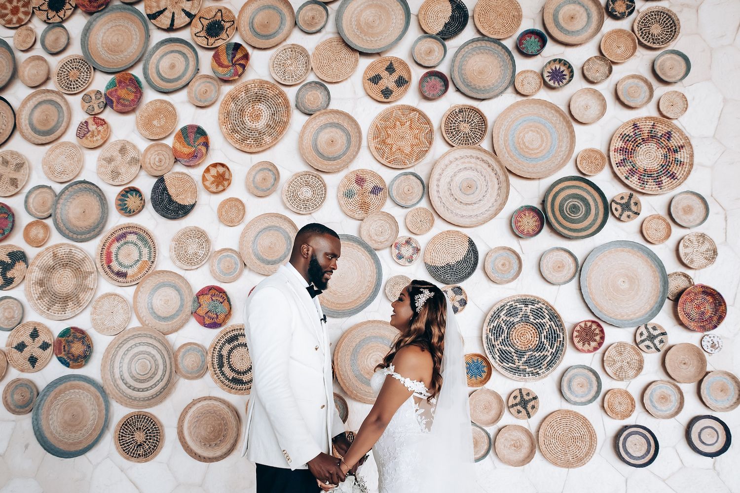 A decorative wall display of woven baskets and plates creates a bohemian wedding backdrop.