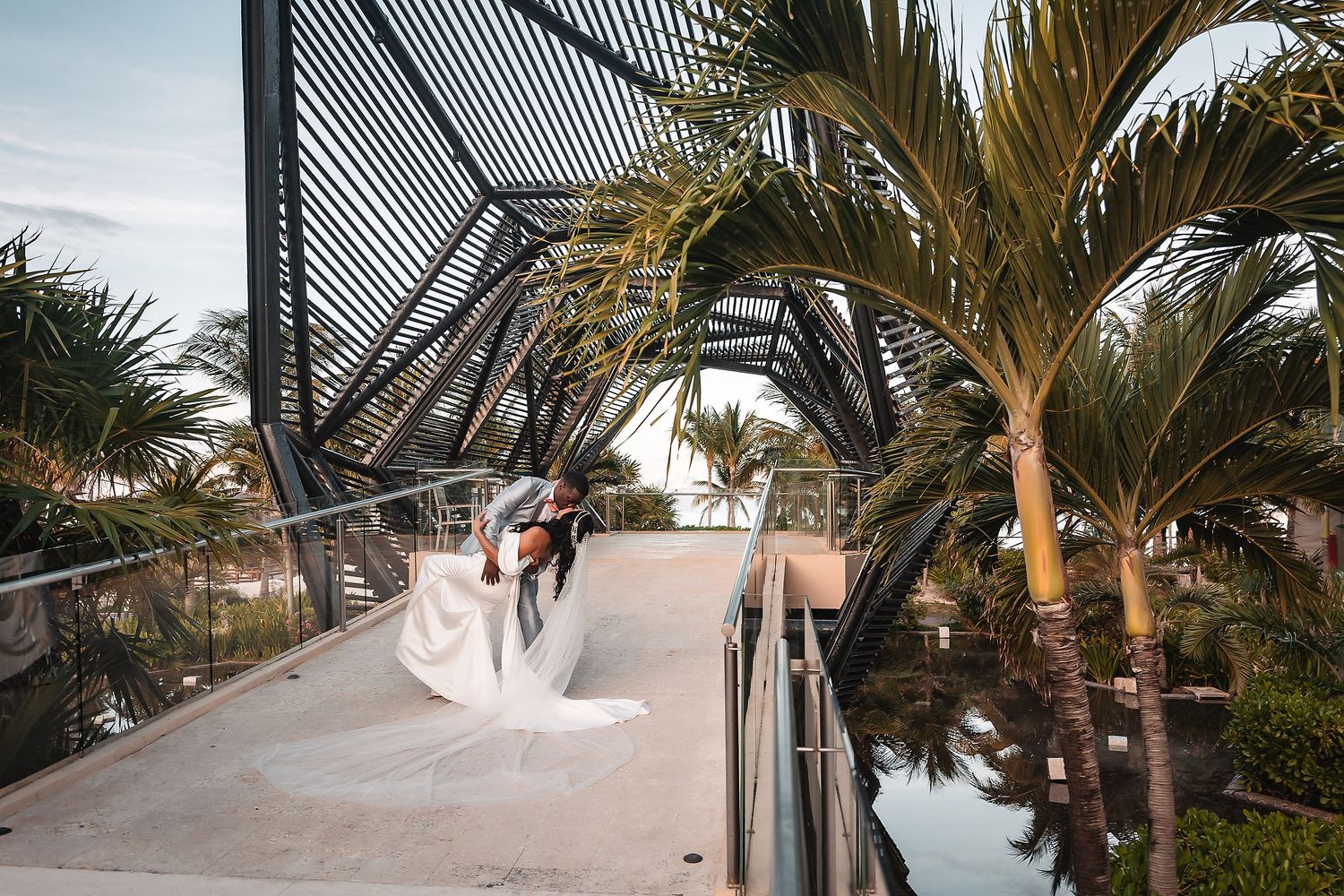 Elegant outdoor wedding venue featuring palm trees and geometric architectural elements at sunset.