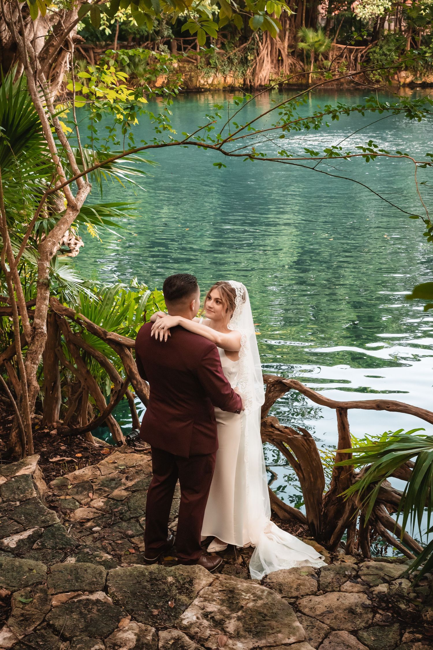 Romantic moment captured by turquoise lagoon with lush tropical landscaping.