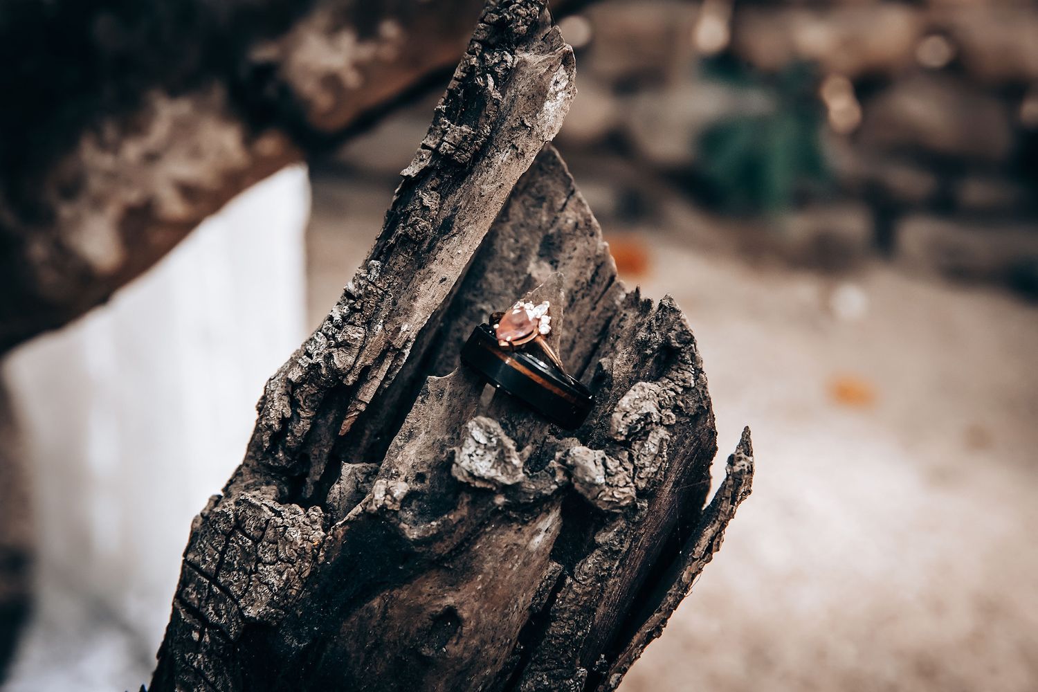 Wedding ring detail shot on weathered wooden surface with dramatic lighting.