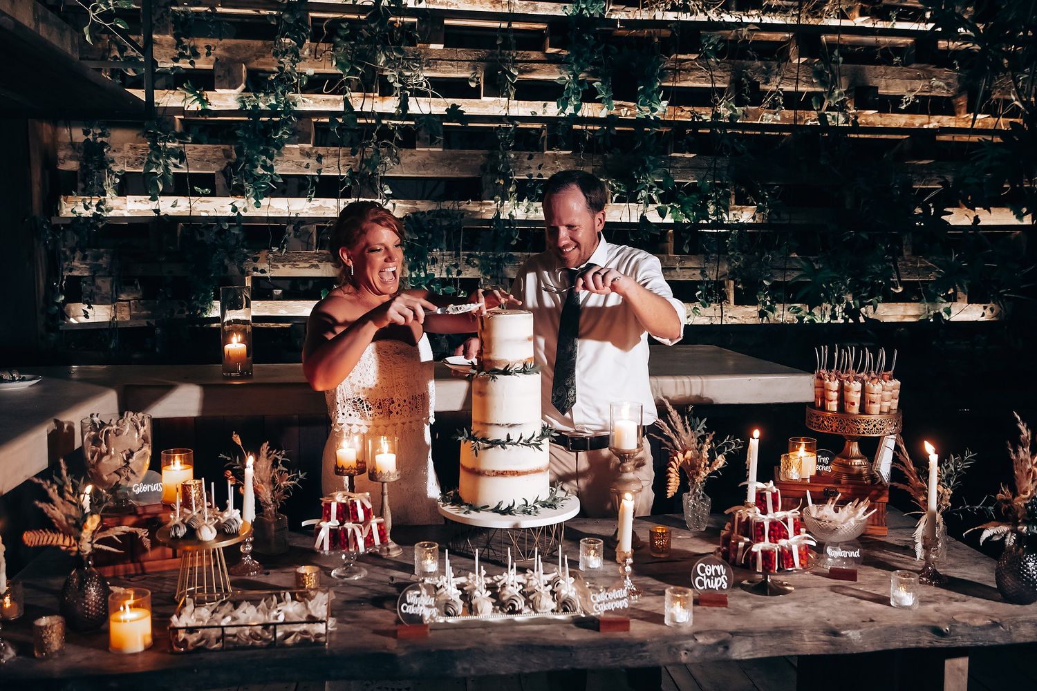 Long wooden table decorated with candles and floral arrangements at a rustic wedding reception.