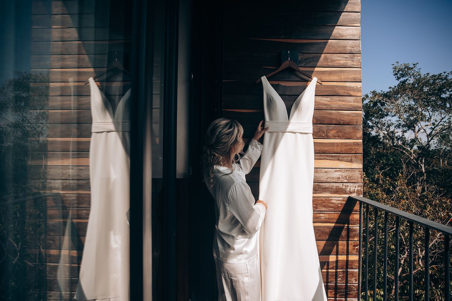Wedding dress preparation scene against wooden wall with natural lighting.