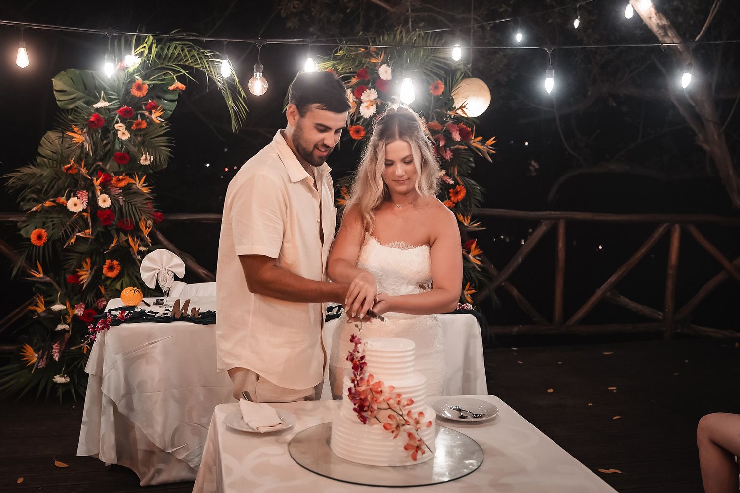 Couple cutting their wedding cake together at decorated head table.