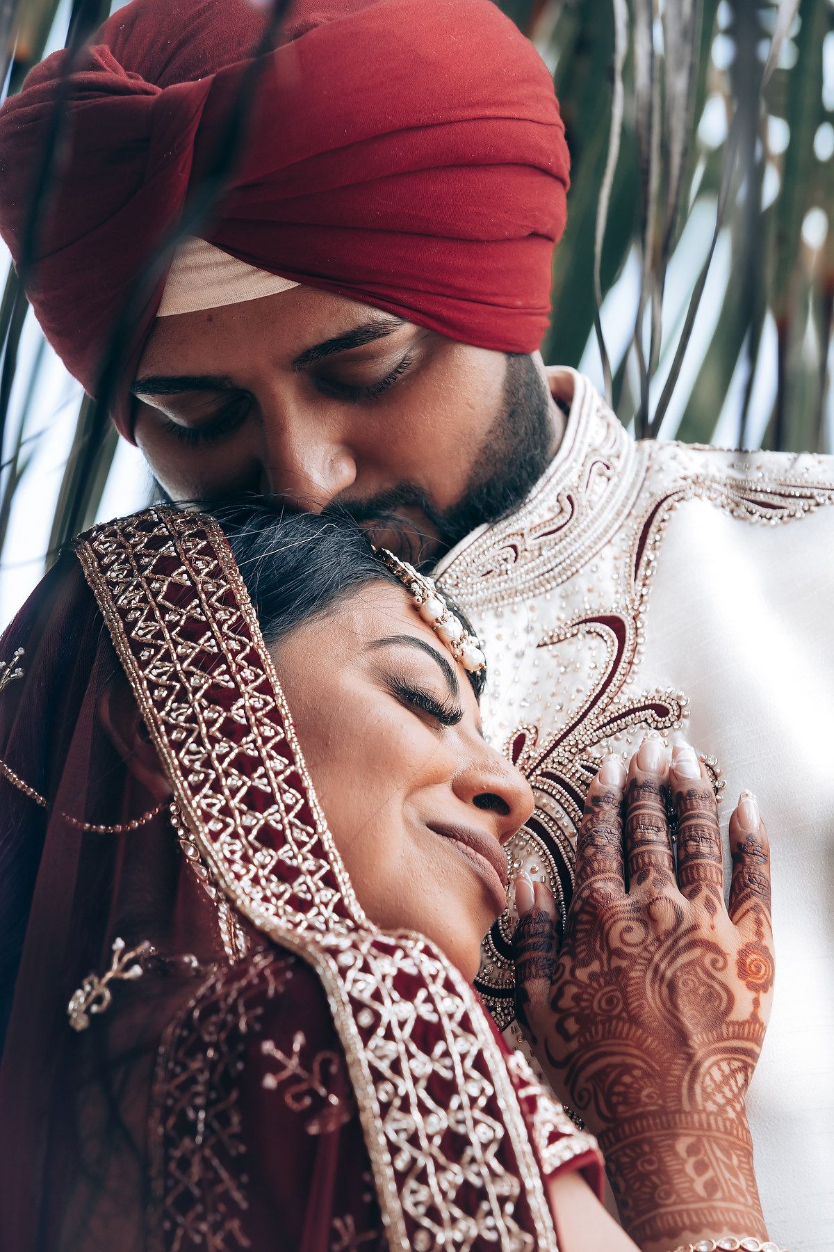 Close-up shot of couple sharing intimate moment with henna decorated hands.