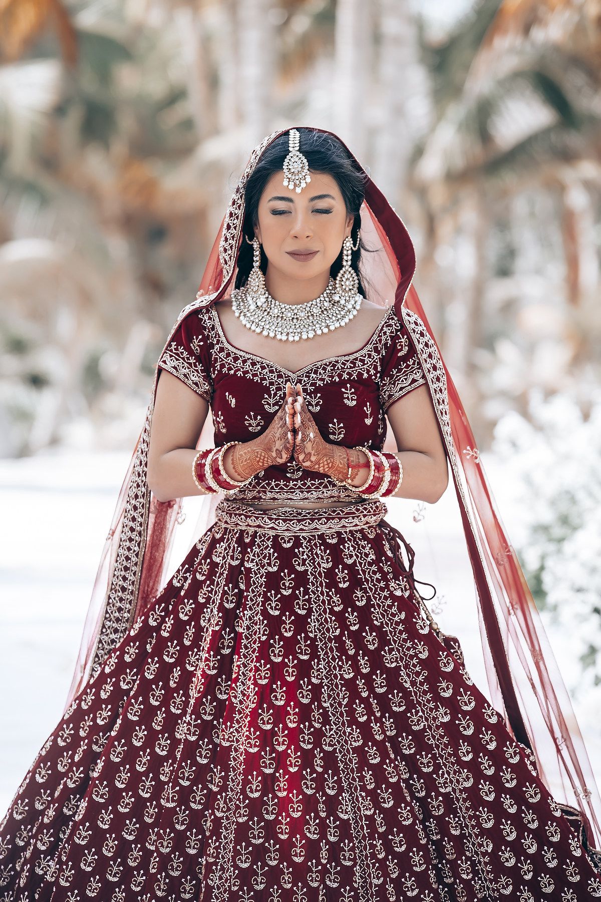 Traditional Indian bridal lehenga in deep burgundy with intricate embroidery and beadwork.