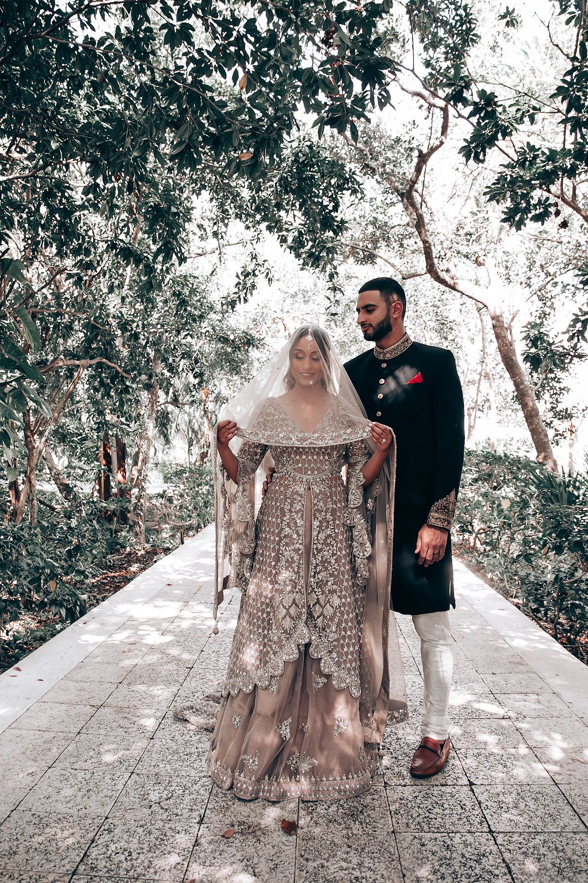 Playful couple photoshoot sequence on a stone path surrounded by lush greenery.