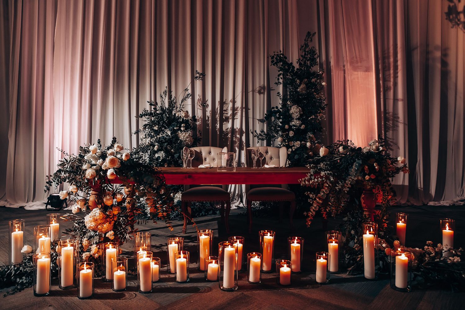 Romantic wedding reception setup with glowing candles and white draping.