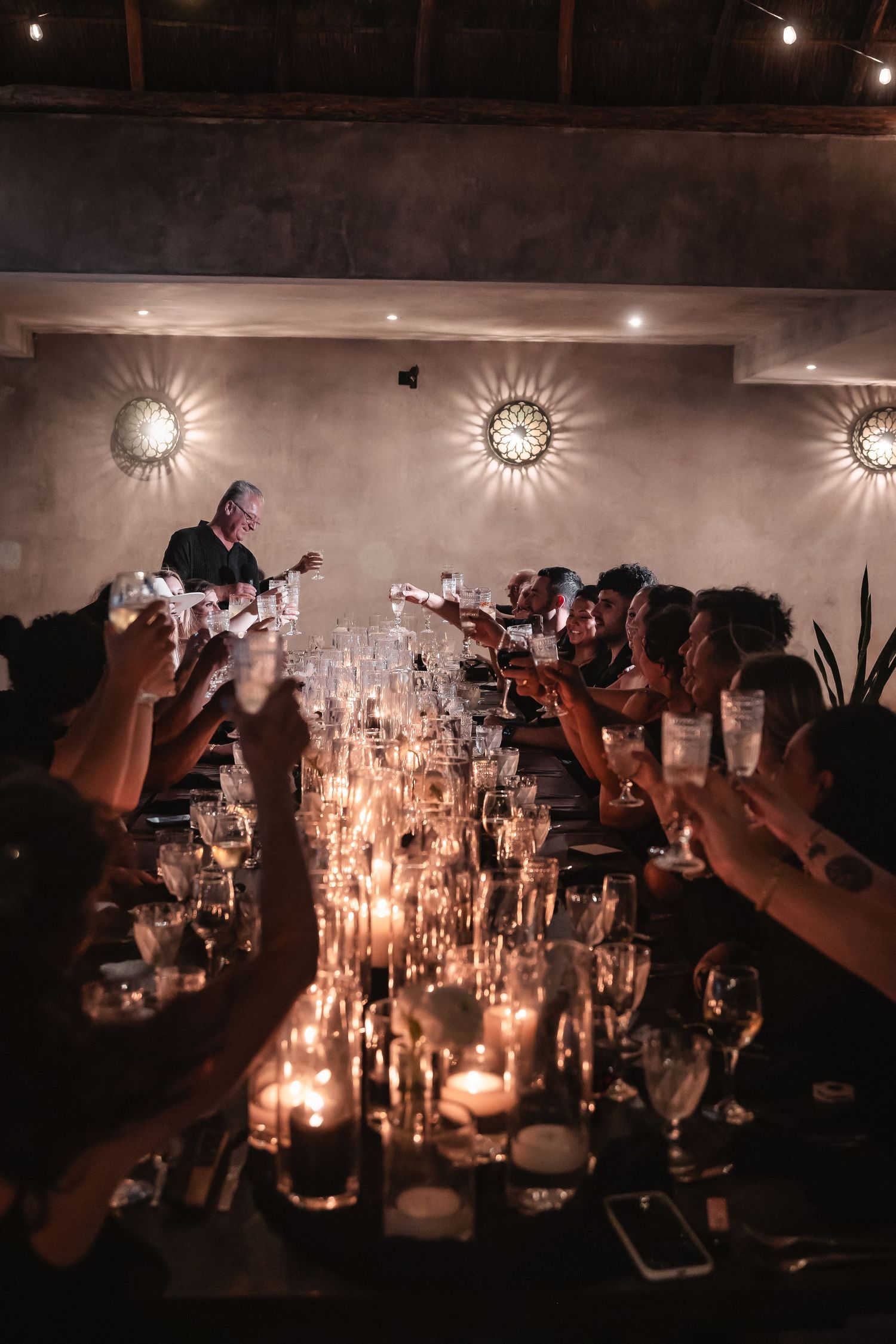 Long tables adorned with glowing candles create an intimate atmosphere at an evening reception.