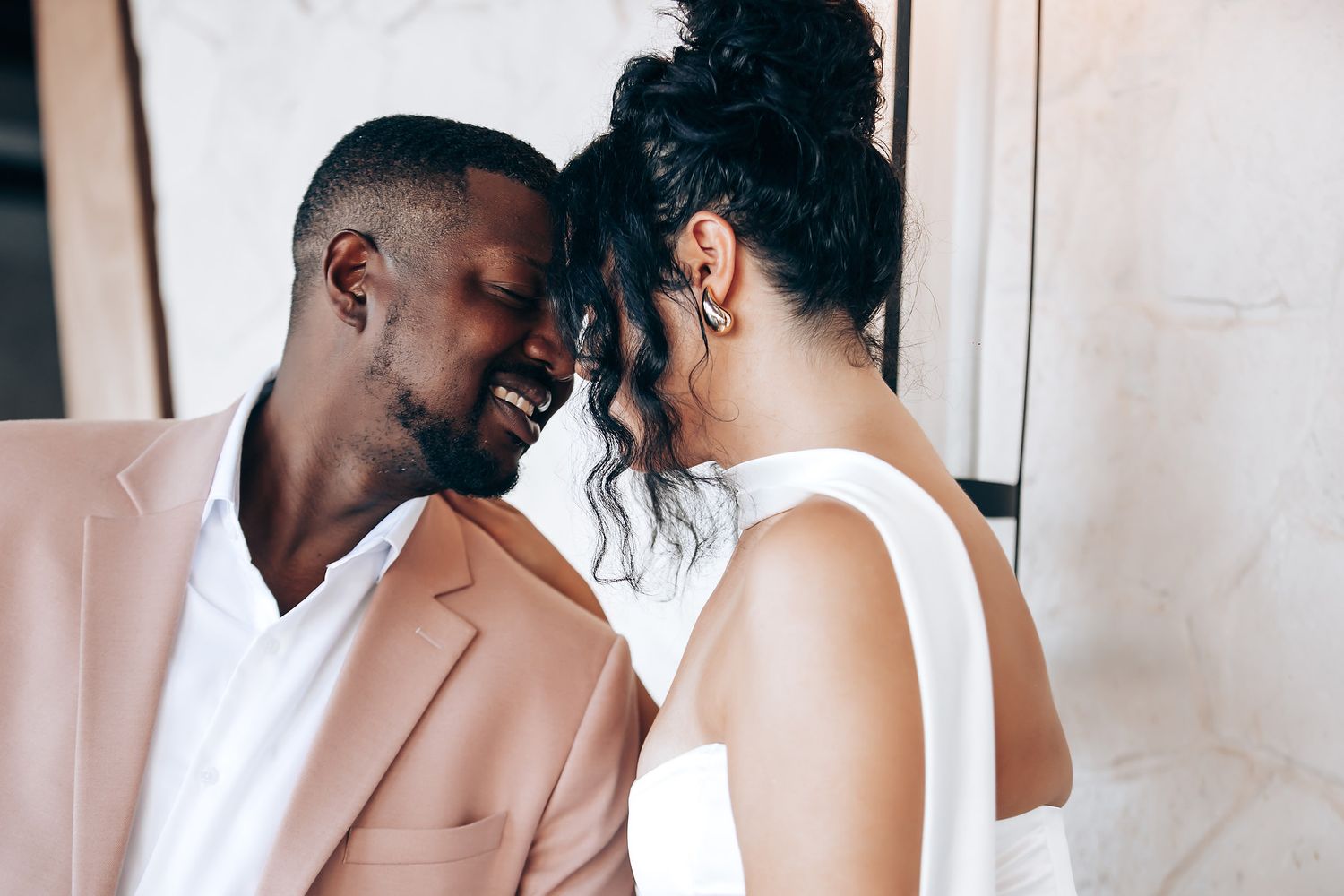 A tender moment between a couple in matching pink and white formal attire.
