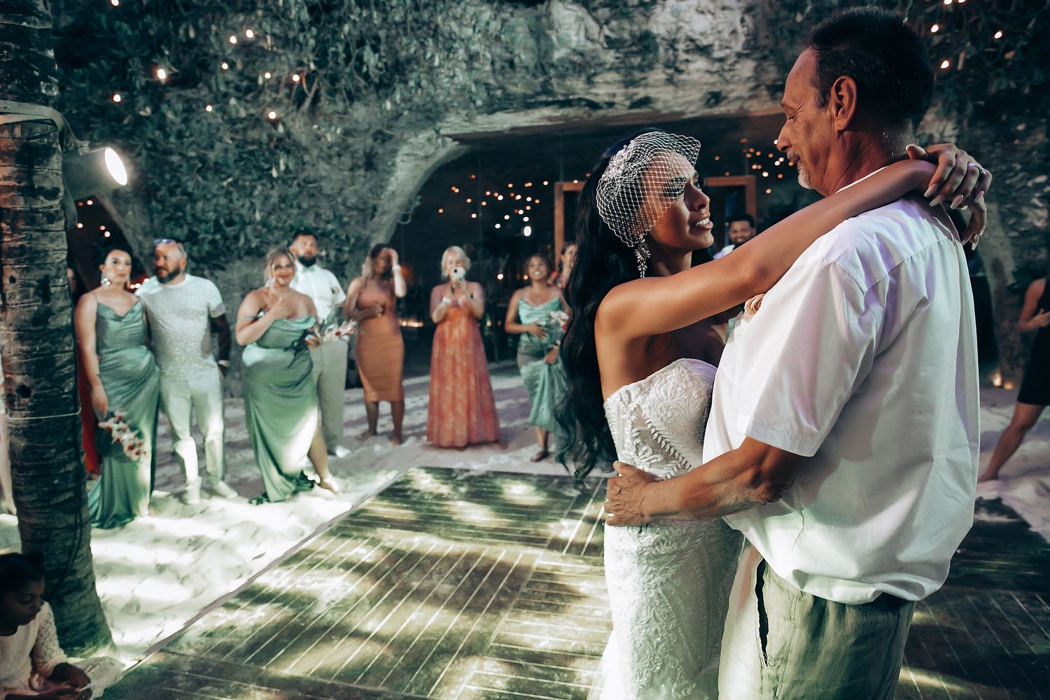Wedding guests dancing and celebrating on an illuminated dance floor during an evening reception.