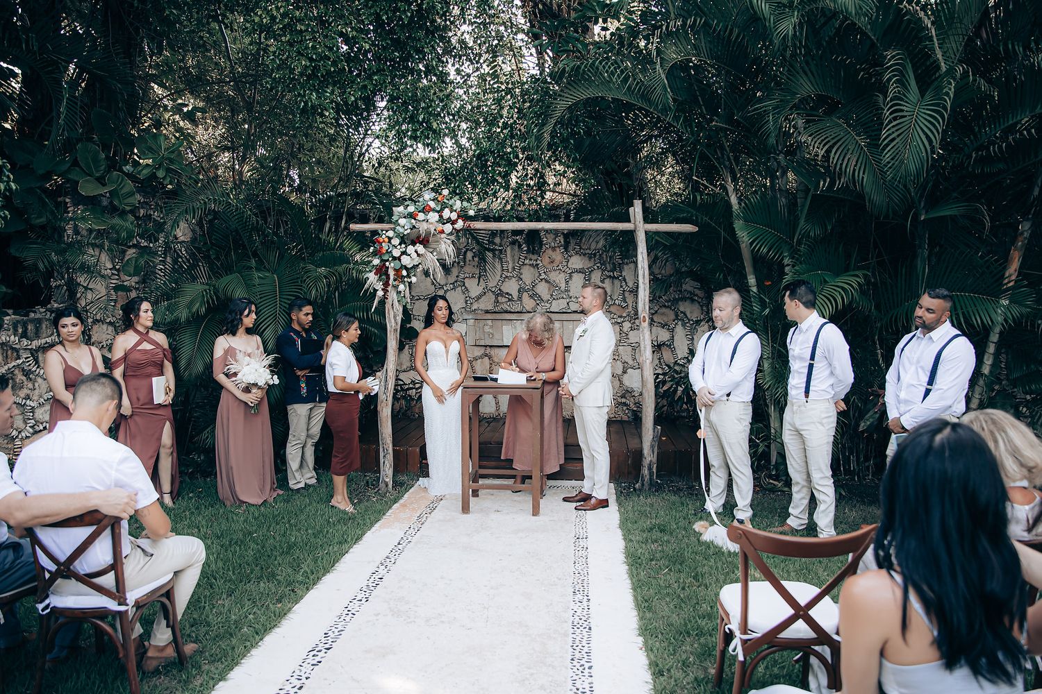 Wedding ceremony setup with white chairs and floral arrangements in an outdoor garden setting.