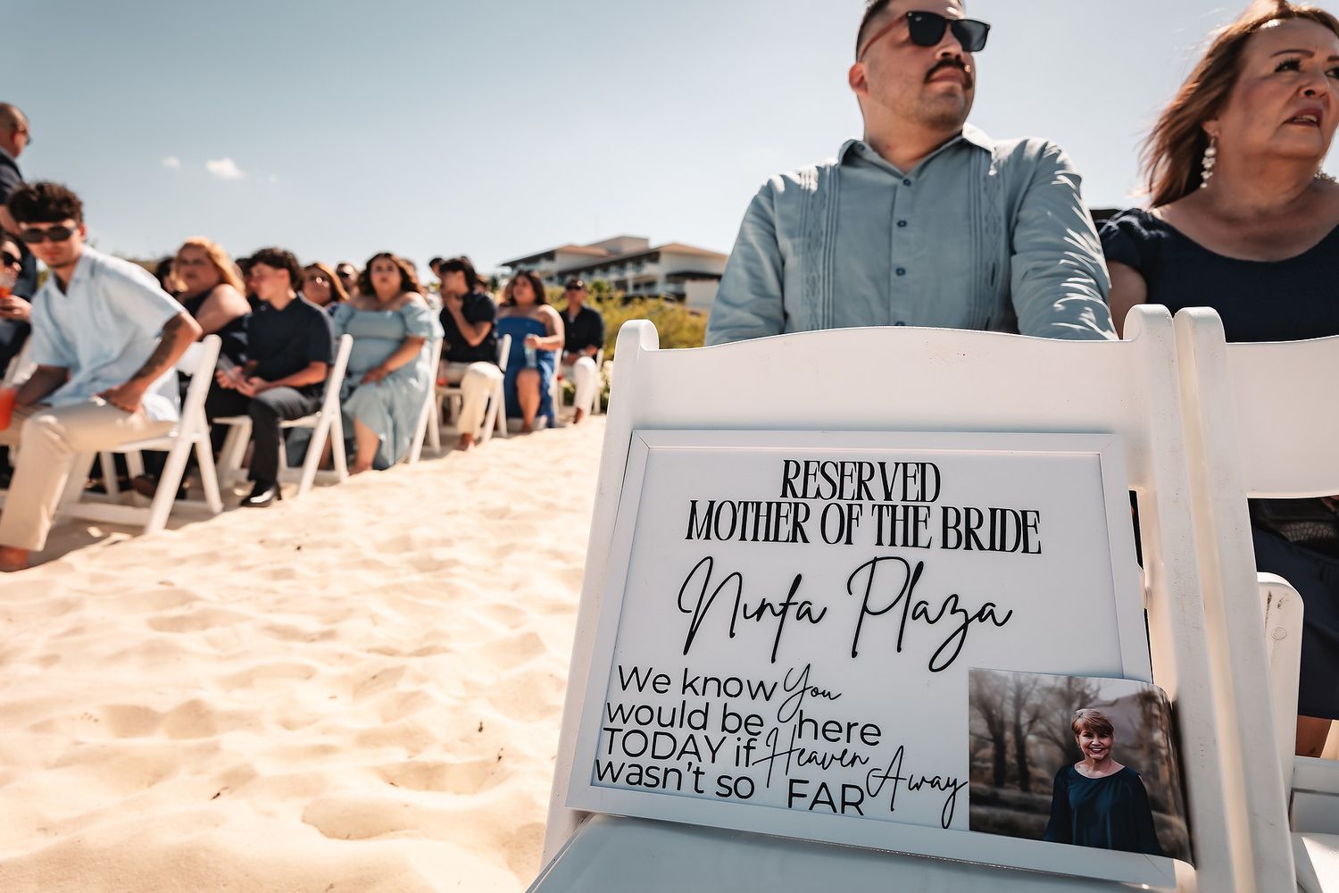 Reserved seat with memorial sign for Mother of the Bride at a beach wedding ceremony.