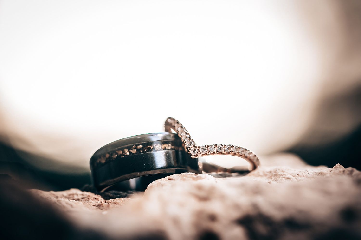 Wedding rings and jewelry arranged artistically with soft bokeh lighting effects in a macro shot.