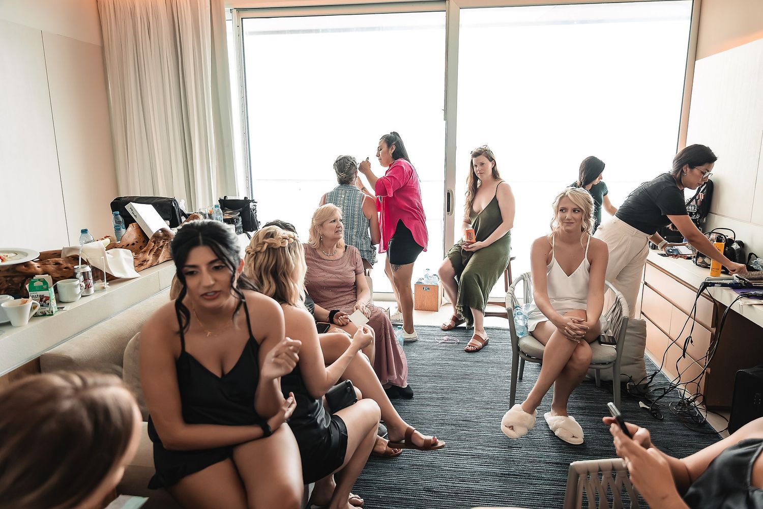 A group of people sitting in a bright room during what appears to be a wedding preparation event.