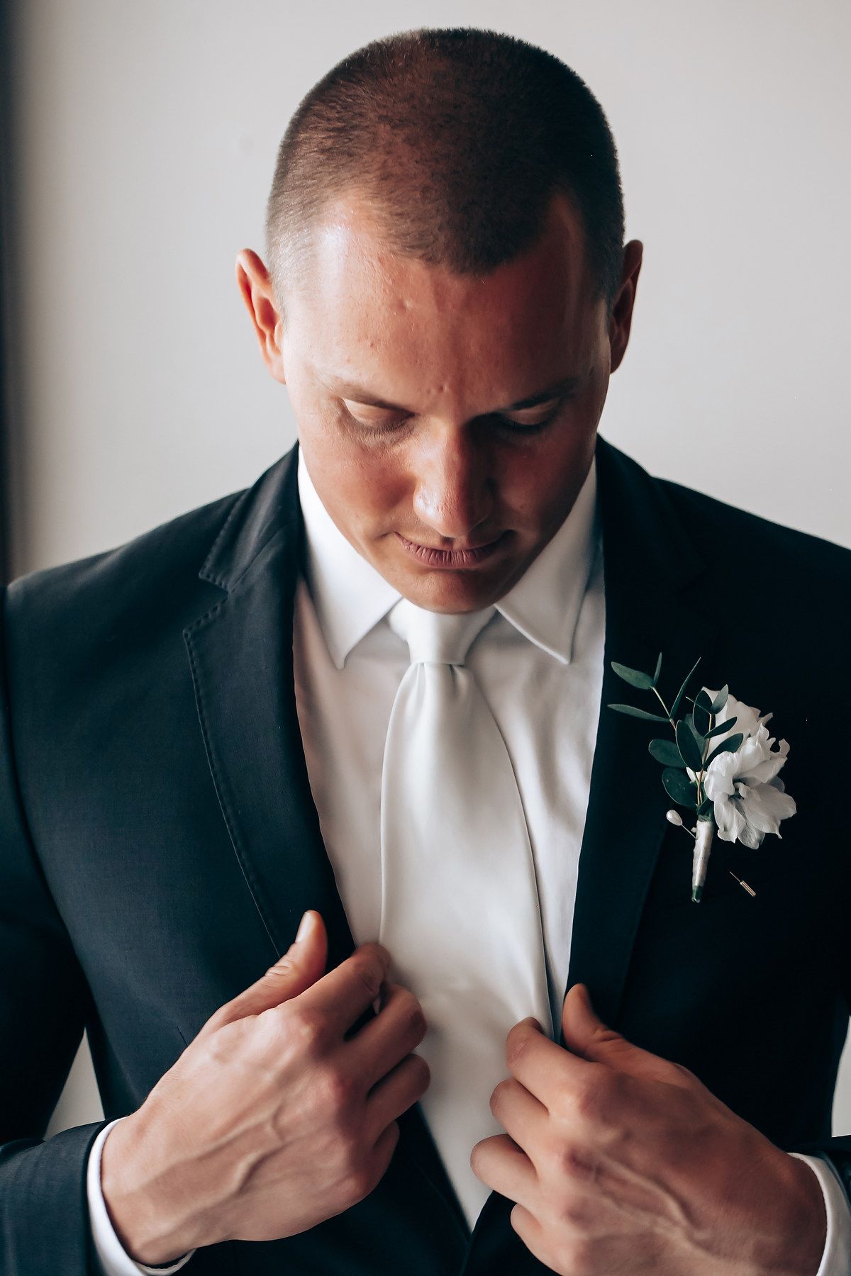 A formal portrait showing a black tuxedo with white boutonniere.
