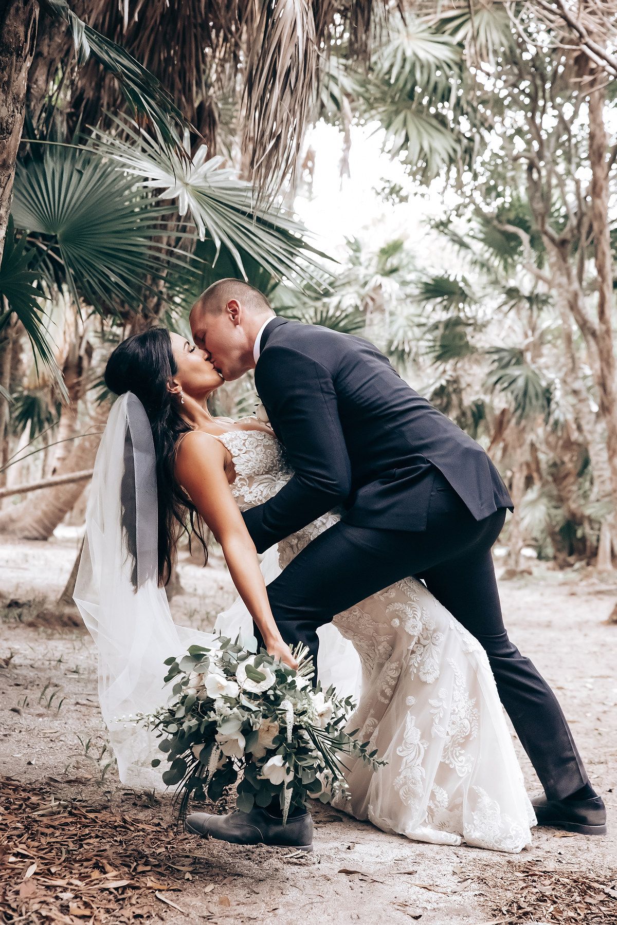 A romantic wedding photo series showing a couple in formal attire sharing intimate moments among tropical palm trees.