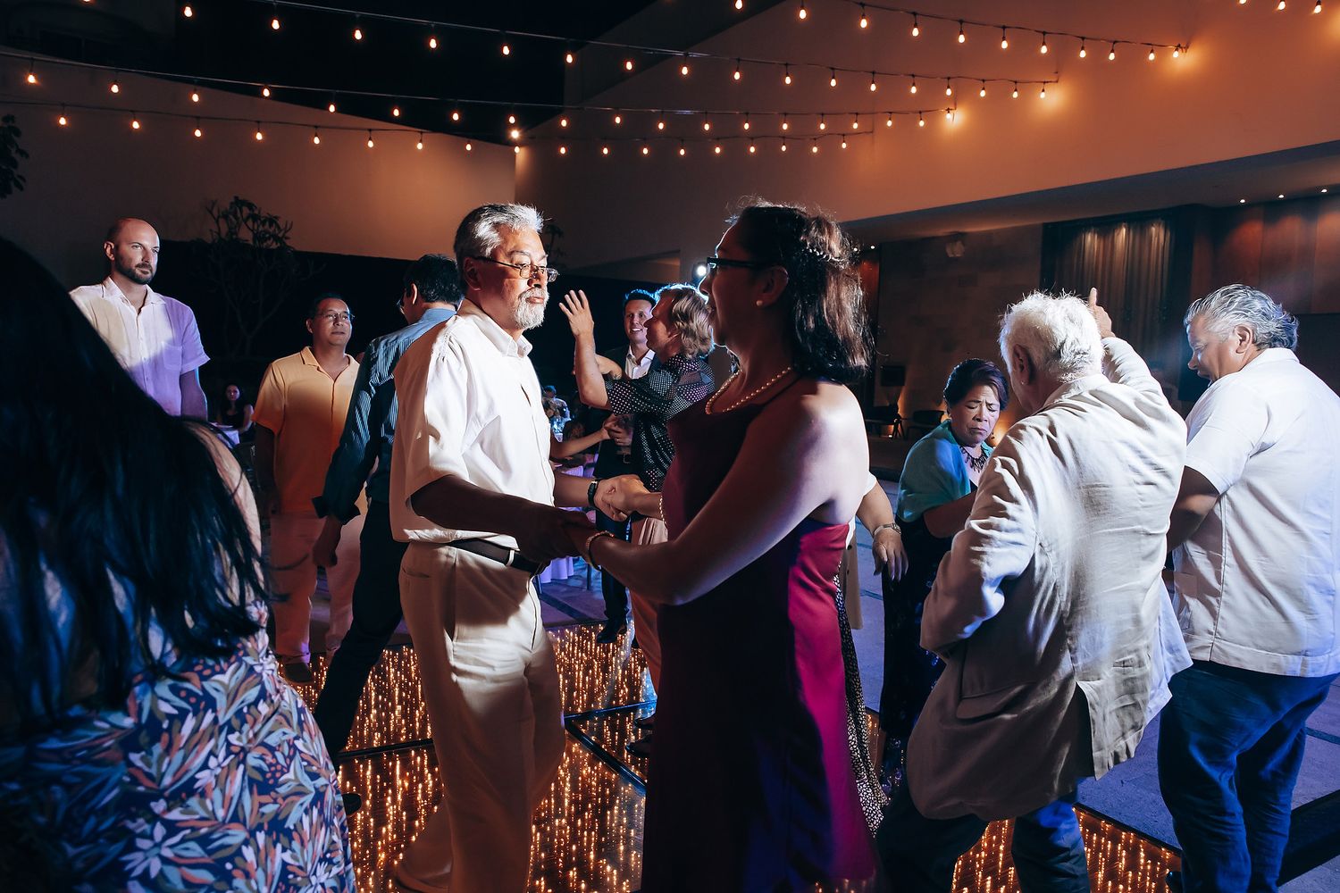 Guests dancing at evening reception under string lights.