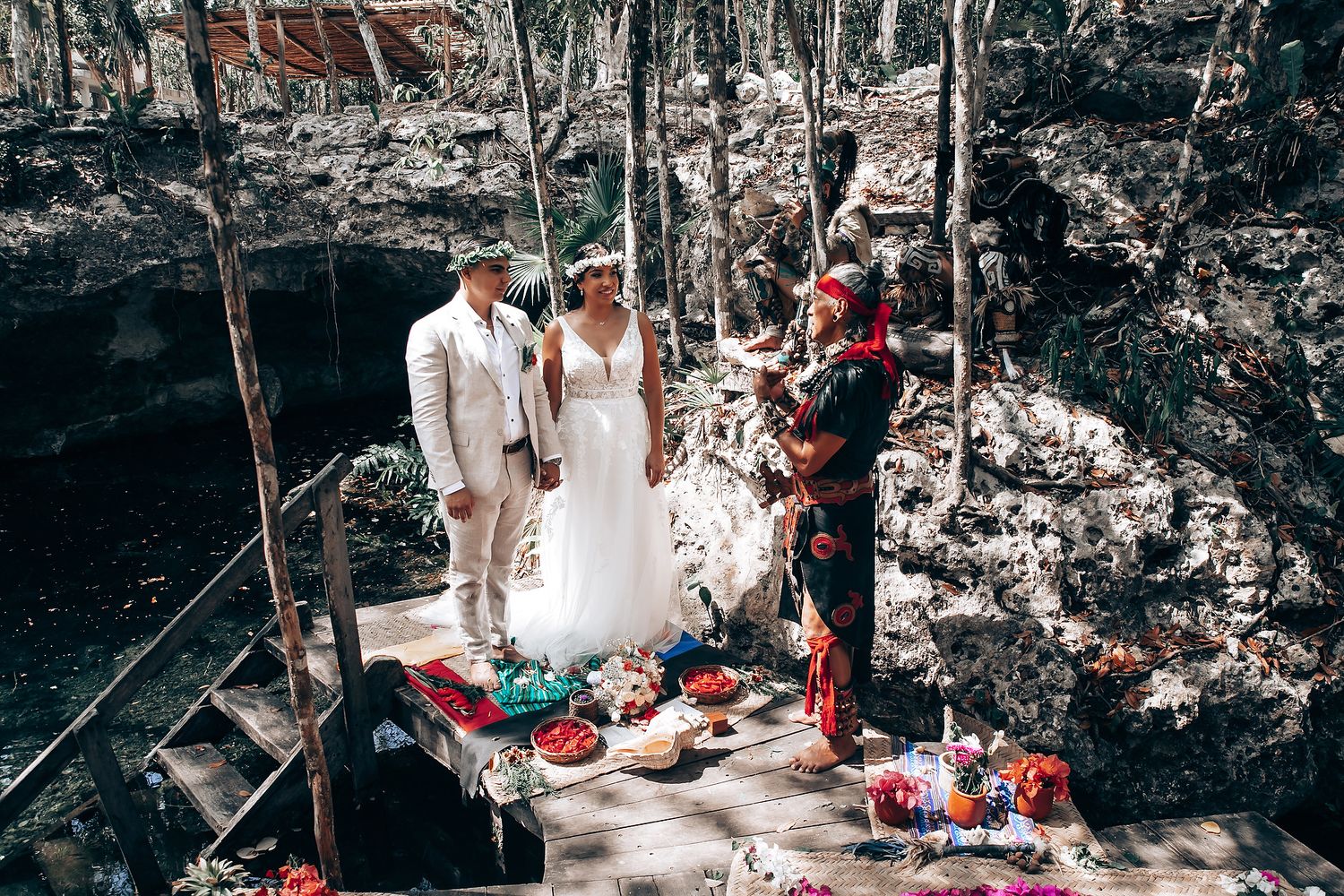 Wedding ceremony setup with colorful decorations on wooden platforms in a forest setting.