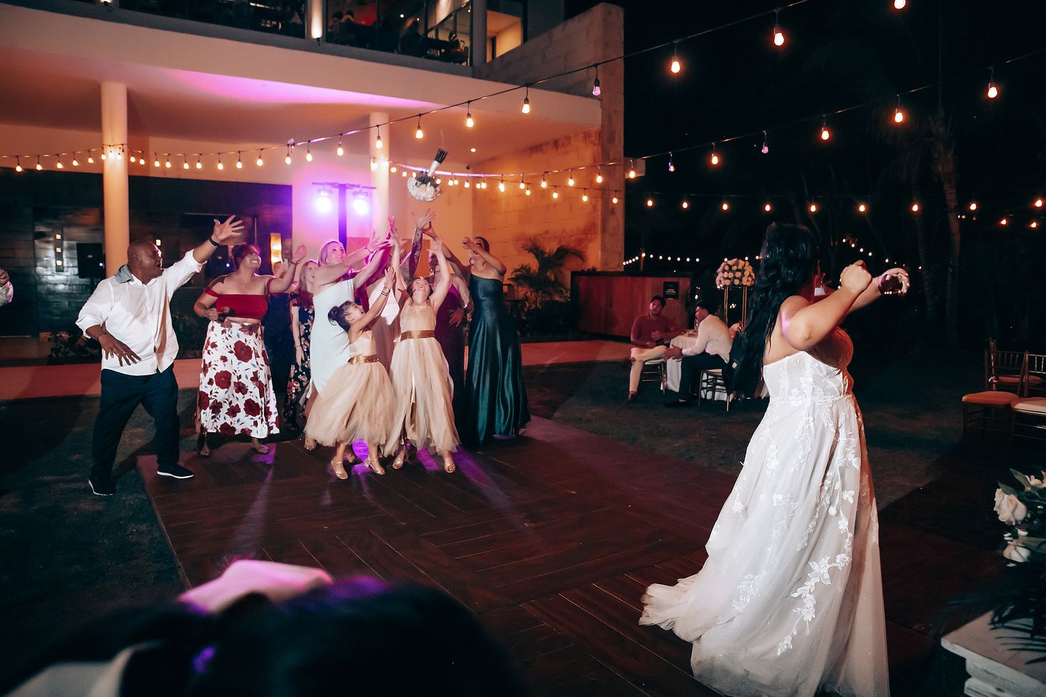 Wedding reception dance floor with string lights and purple ambient lighting.