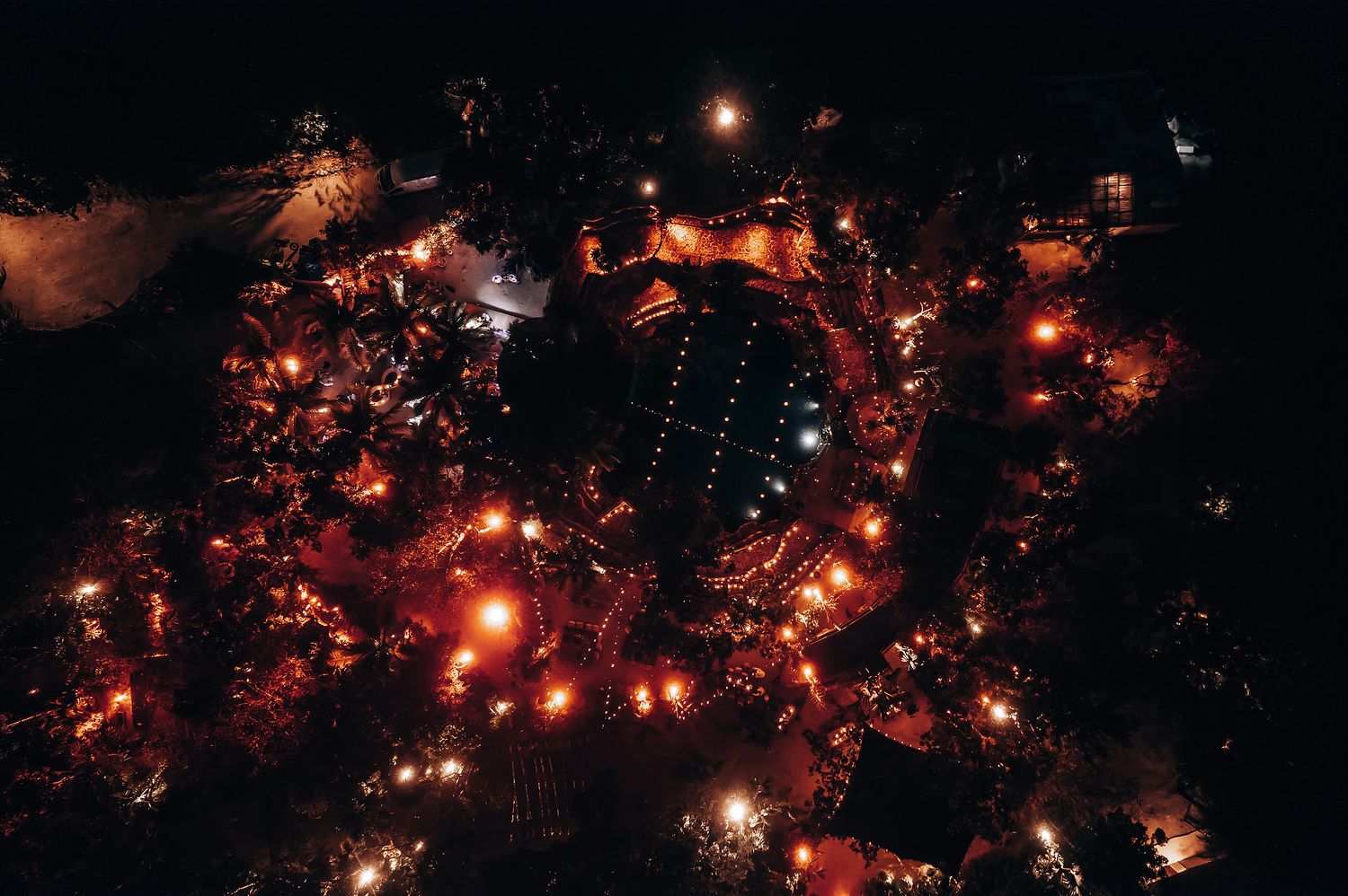 Warm twinkle lights sparkle against the dark night sky at an outdoor wedding venue.