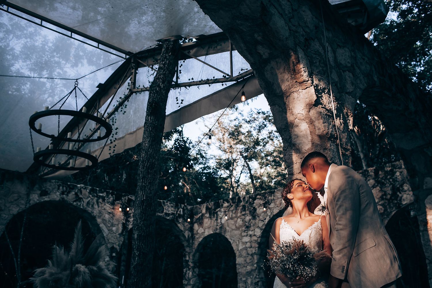 A dramatic wedding portrait with moody lighting and atmospheric smoke effects in a forest setting.