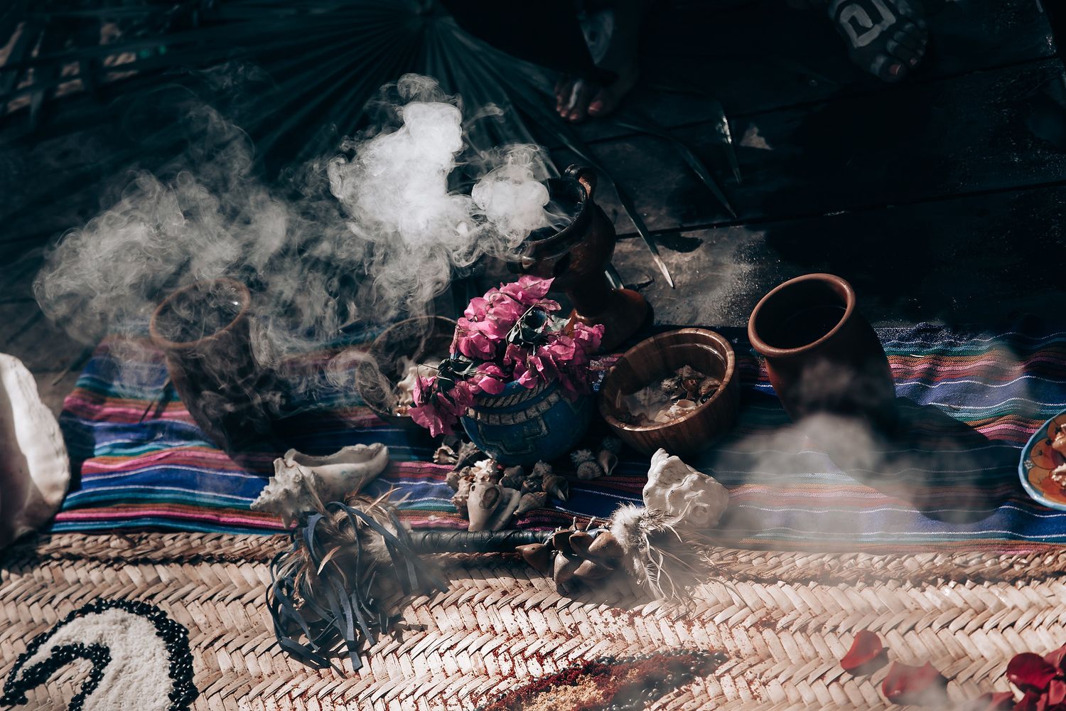 Steaming hot tea and dried flowers arranged on a striped textile with traditional Middle Eastern accessories.