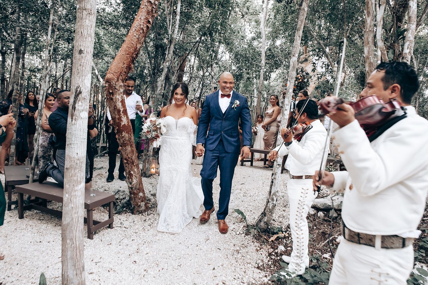 Outdoor forest wedding ceremony with musicians playing among eucalyptus trees.