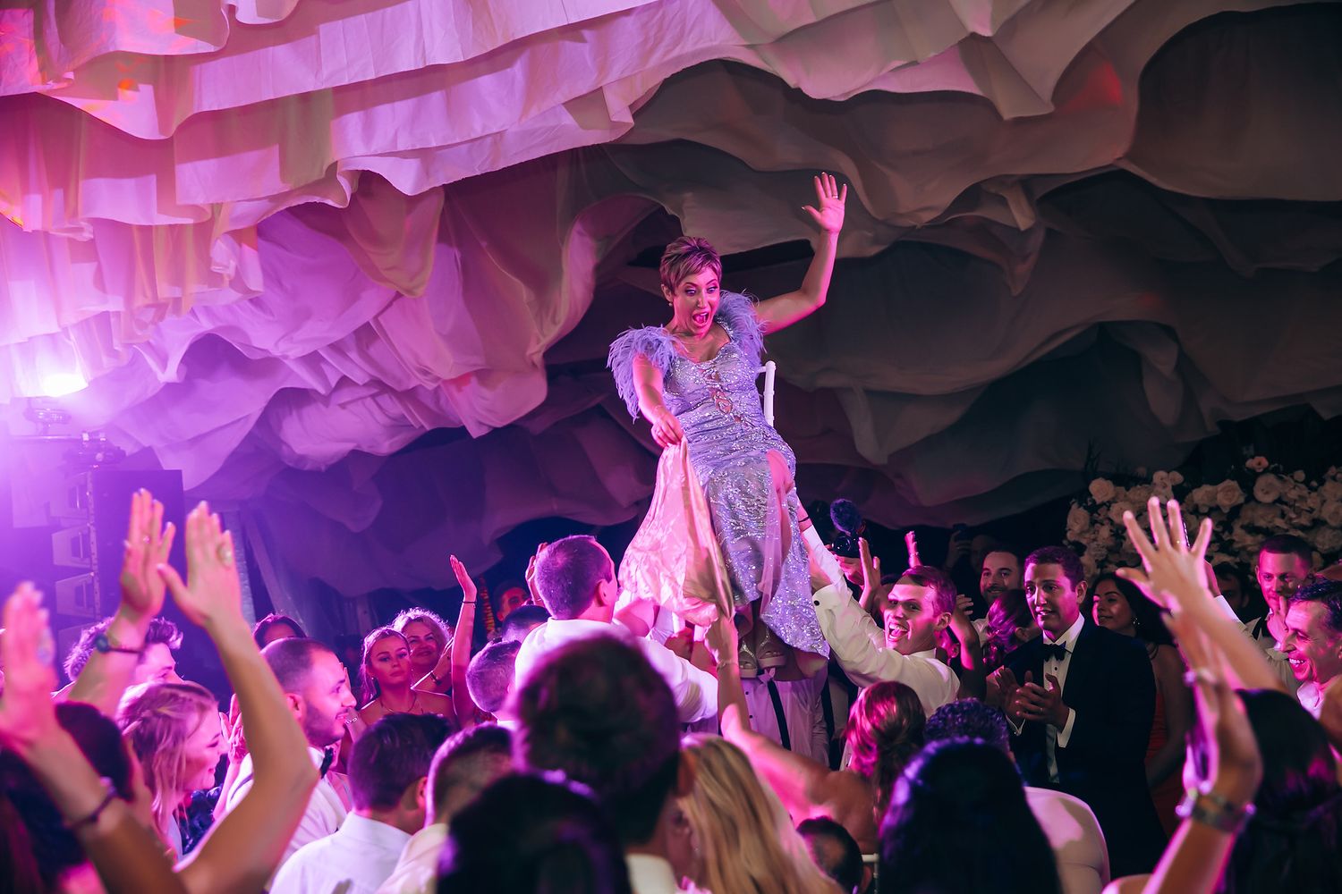 Energetic wedding reception dance floor with purple and red lighting effects.